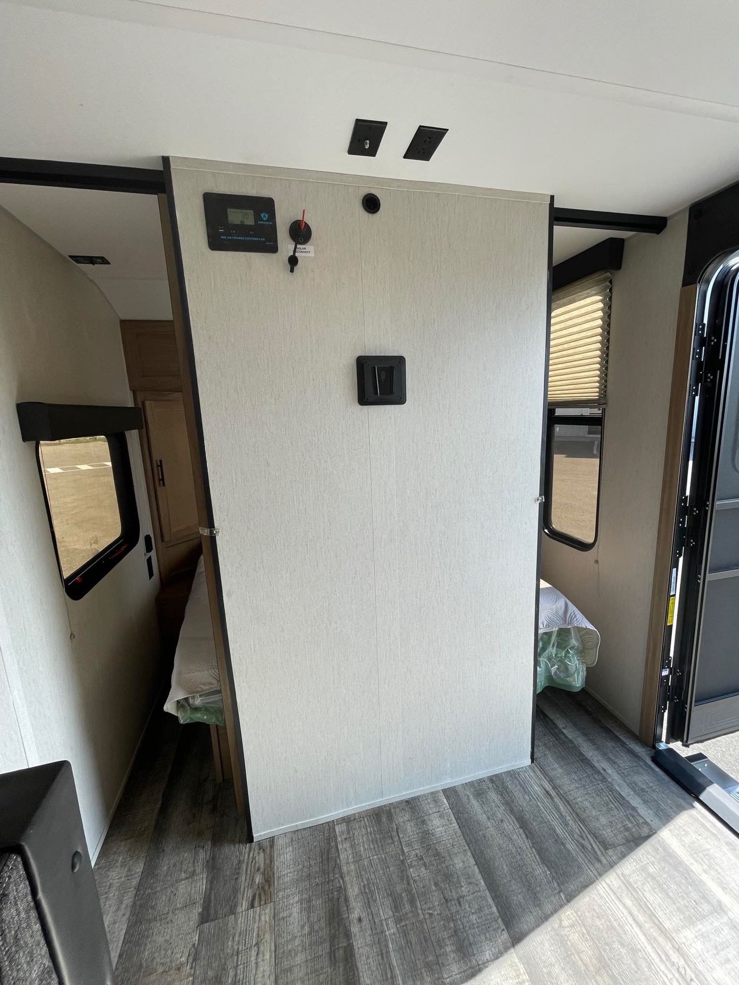 RV rental interior showing a central dividing wall with a solar charge controller, bed area, and entry door.. Forest River Cherokee Wolf Pup 2023