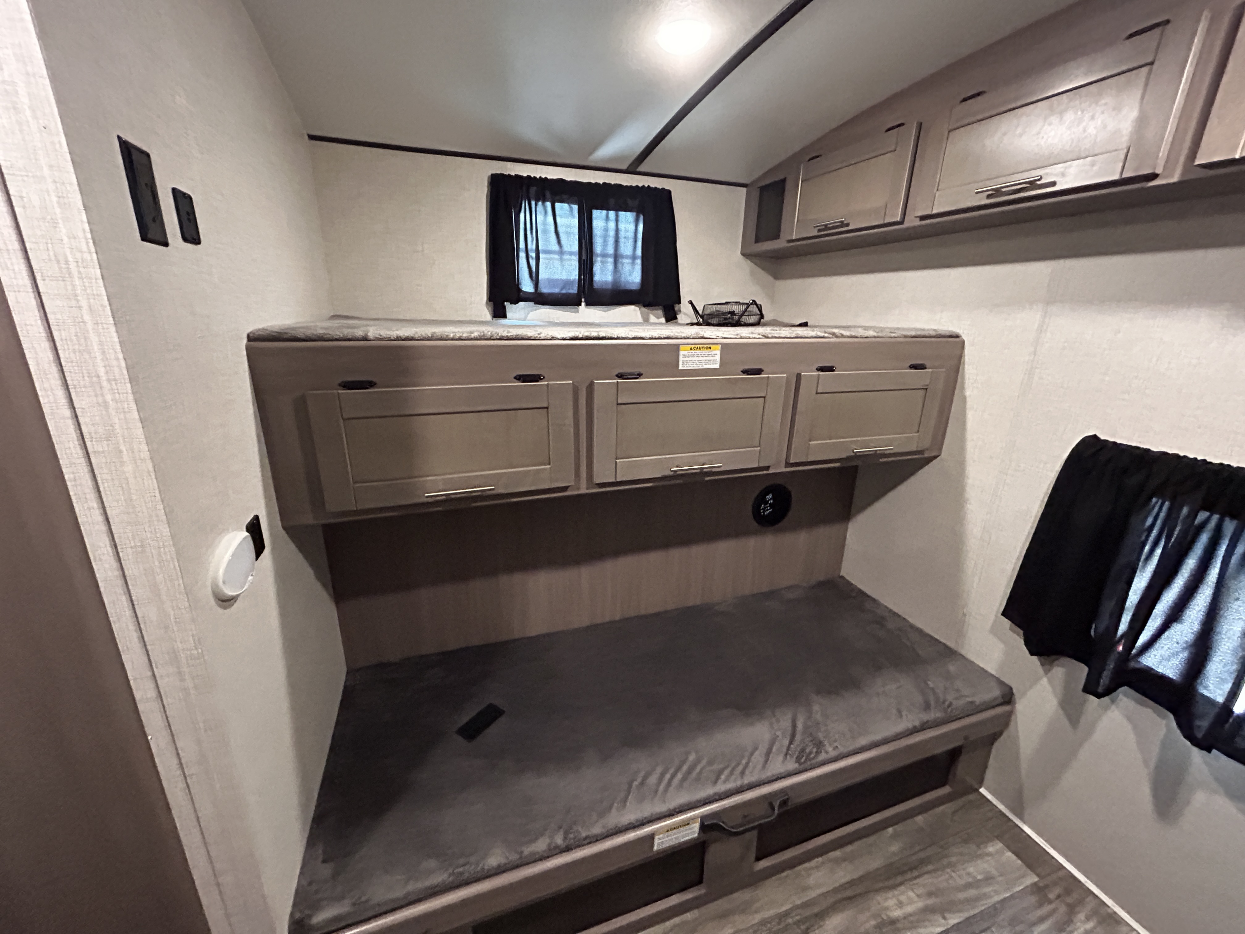 Functional rv rental bunk bed area with integrated storage below the upper bunk, overhead cabinets, and a lower sleeping spot.. Crossroads Sunset 2021