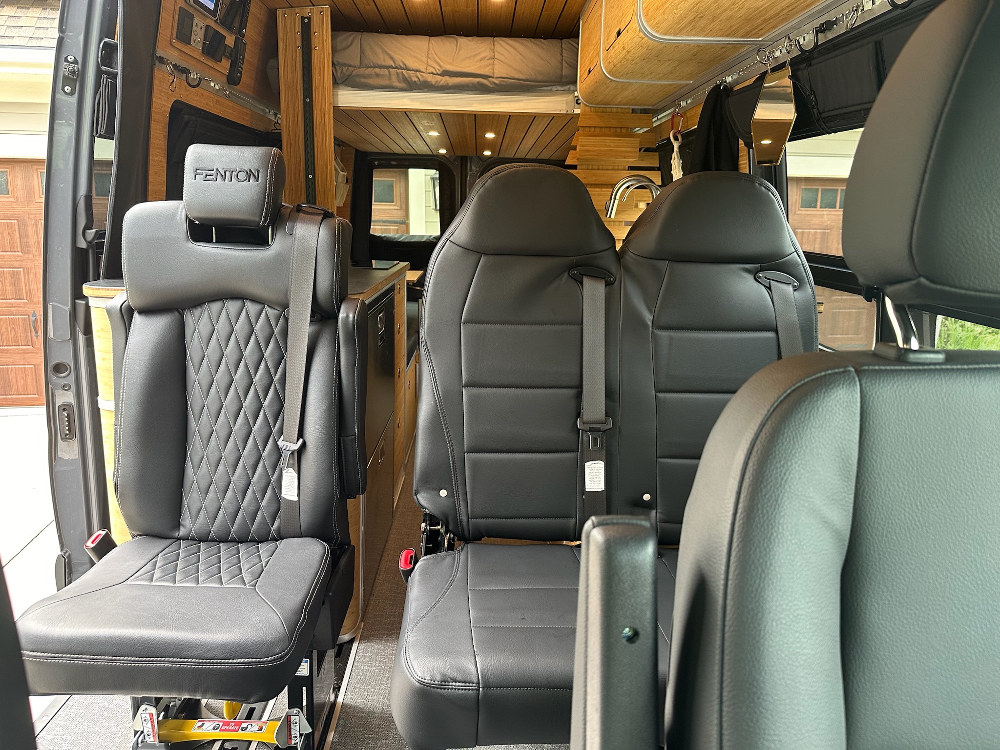 Premium RV rental interior shows black leather seating, including a FENTON branded seat with diamond stitching, and wood-paneled bunk bed.. Mercedes-Benz Sprinter 2024