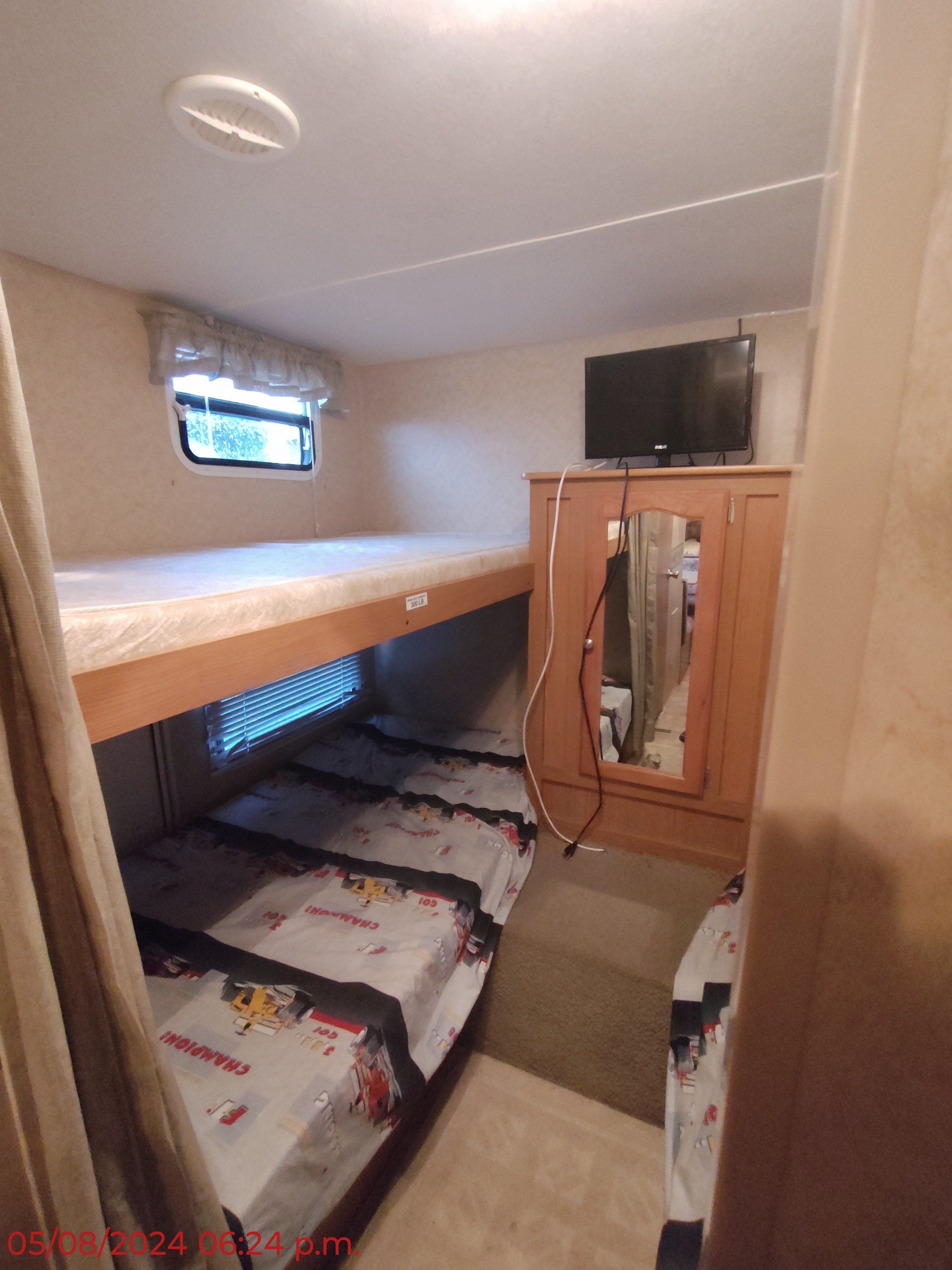 Cozy RV rental bunk bed sleeping area with a raised top bunk, two lower beds, a window, and a TV/cabinet.. Dutchmen Dutchmen 2007