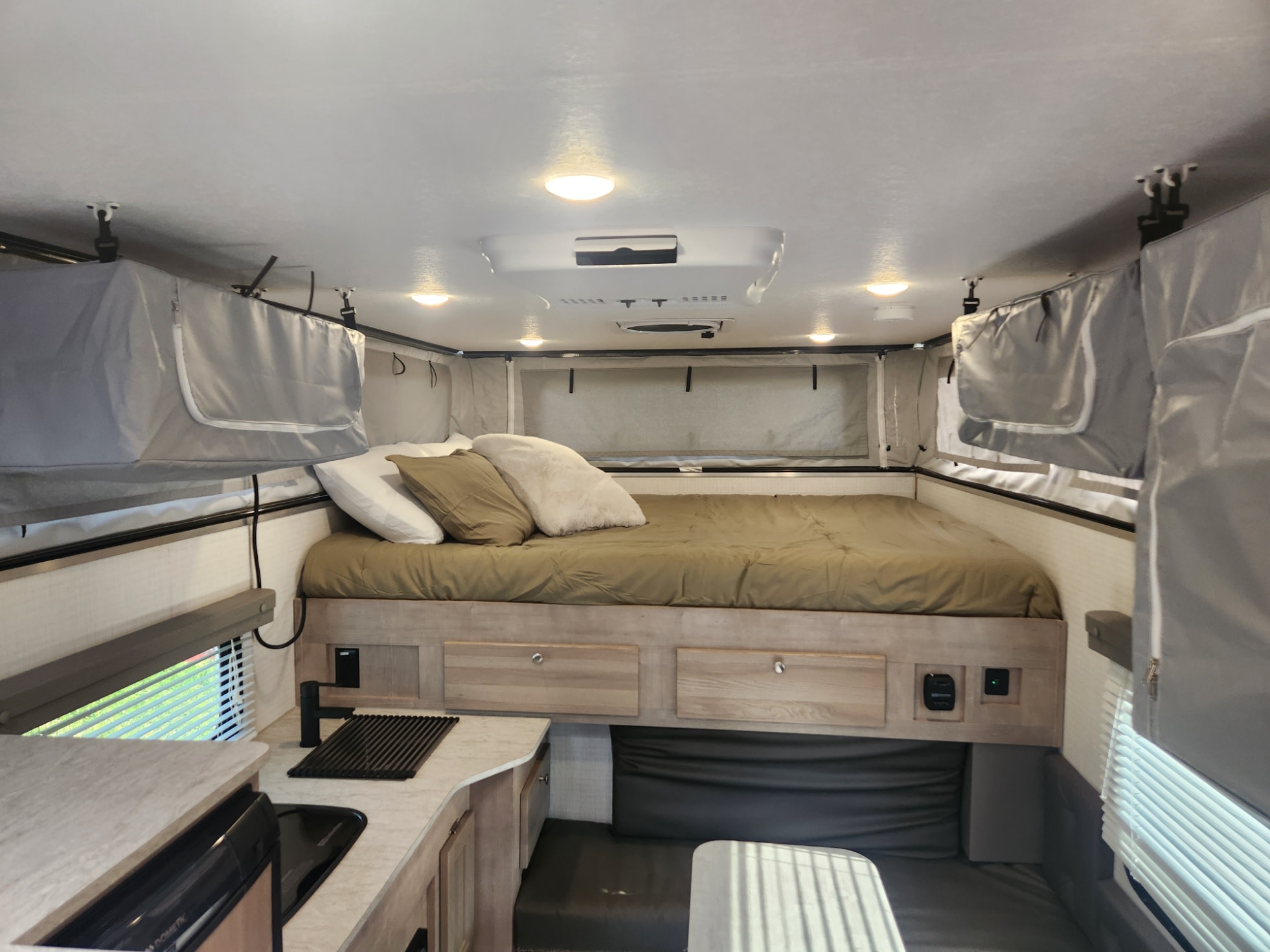 Spacious pop-up camper interior for RV rental. Features a large bed, kitchen, and dining area with blinds.. Palomino SS1500 2023