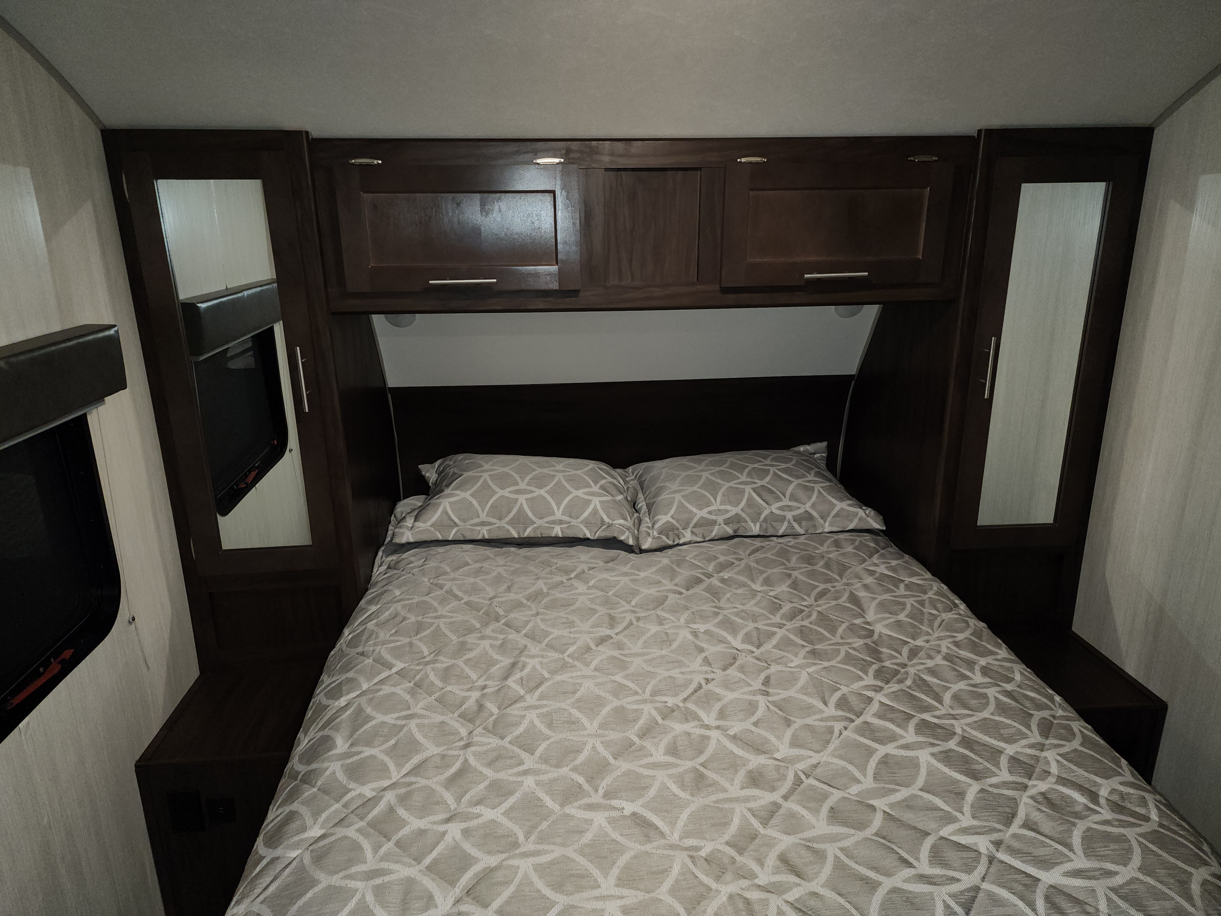 RV rental: Compact bedroom with a comfortable patterned bed, mirrored wardrobes, and charging shelf.. Forest River Cherokee 2020