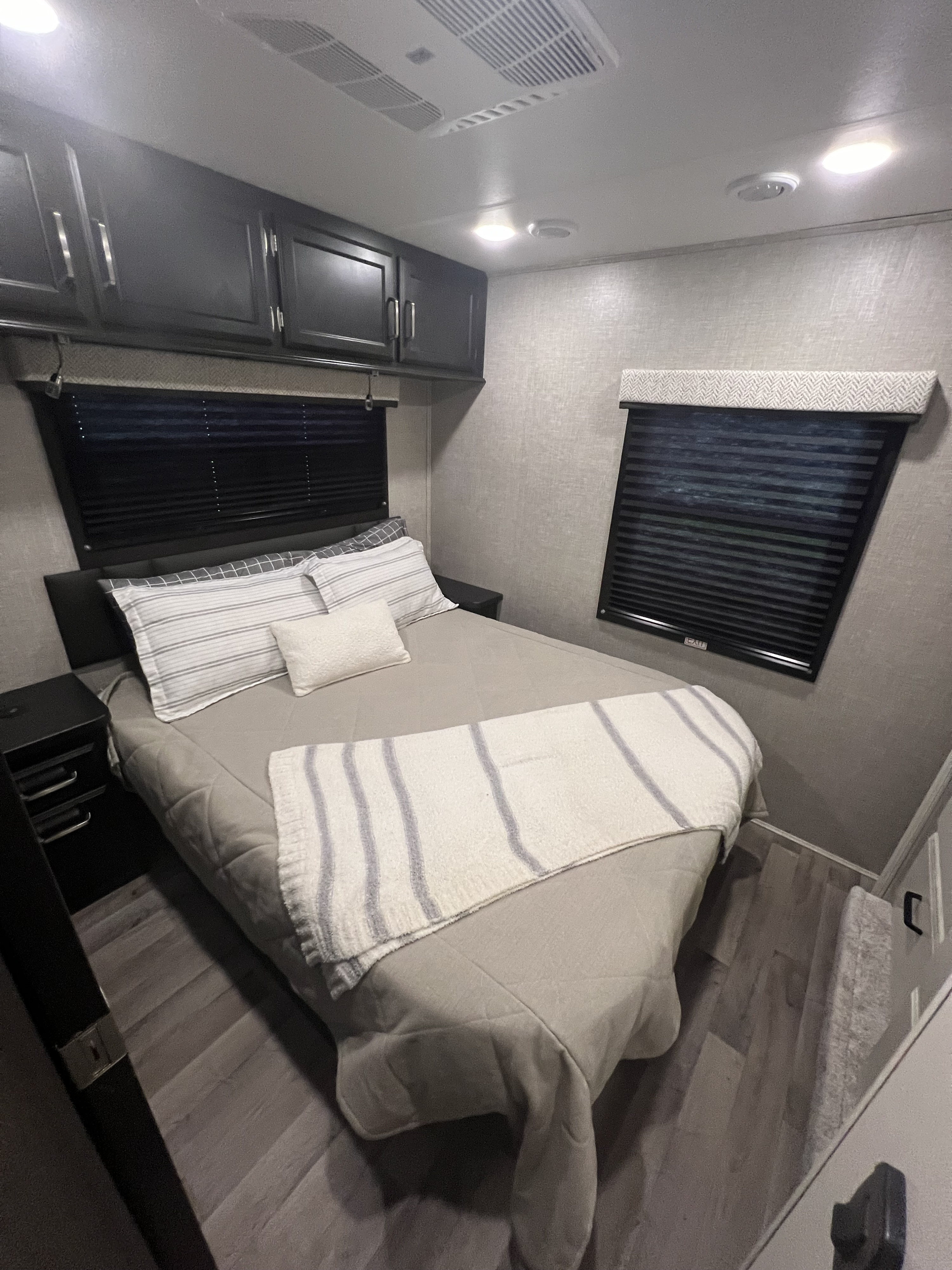 Cozy bedroom in an RV rental, featuring a queen bed, overhead storage, and window blinds for comfort and privacy.. Entegra Coach Odyssey 2023