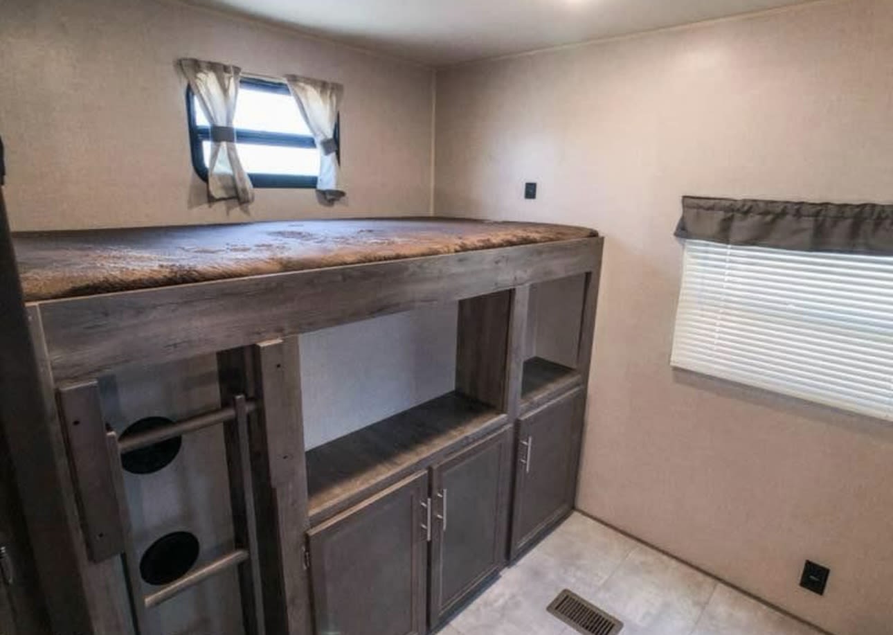 This RV rental's bunk area features a top bed, lower storage units, a ladder, and windows, optimizing compact living space.. Forest River Aurora Aurora 2022