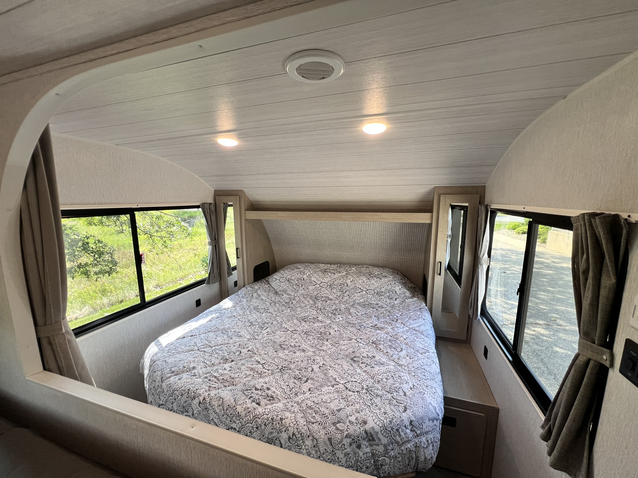 Cozy RV rental bedroom with a large patterned bed, bright windows, and overhead lights, perfect for a comfortable stay.. Forest River Salem Cruise Lite 2024