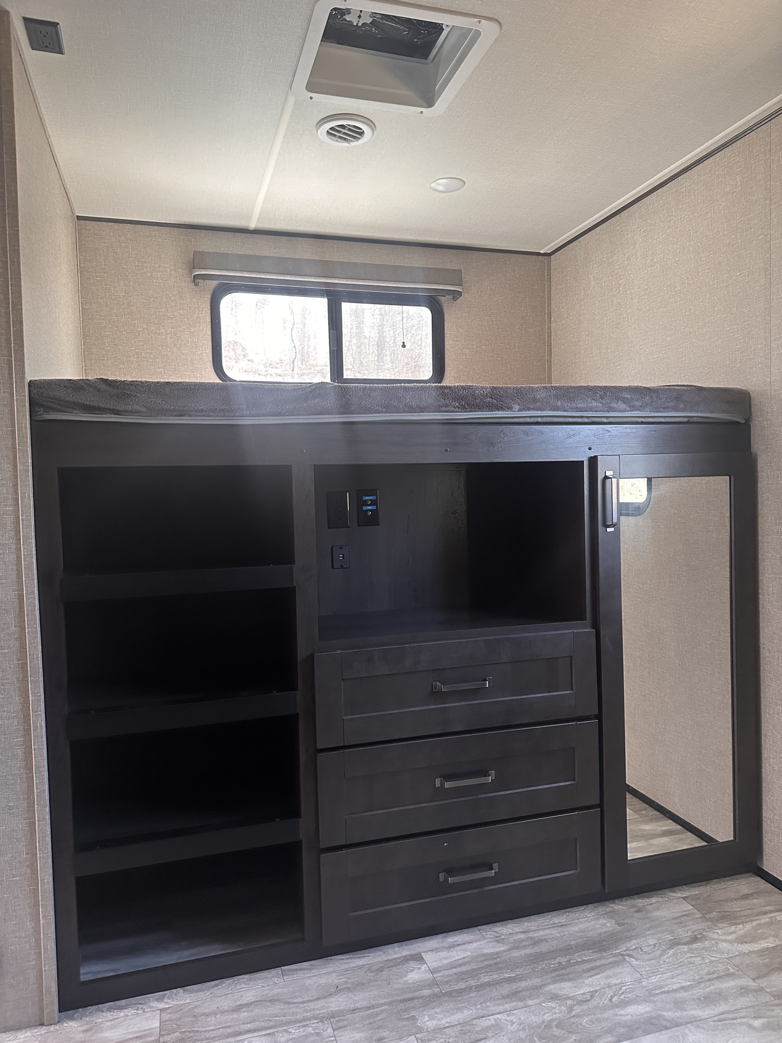 RV rental bunk beds and storage unit with shelves, drawers, mirror, and power outlets for a functional space.. Grand Design Reflection 2022