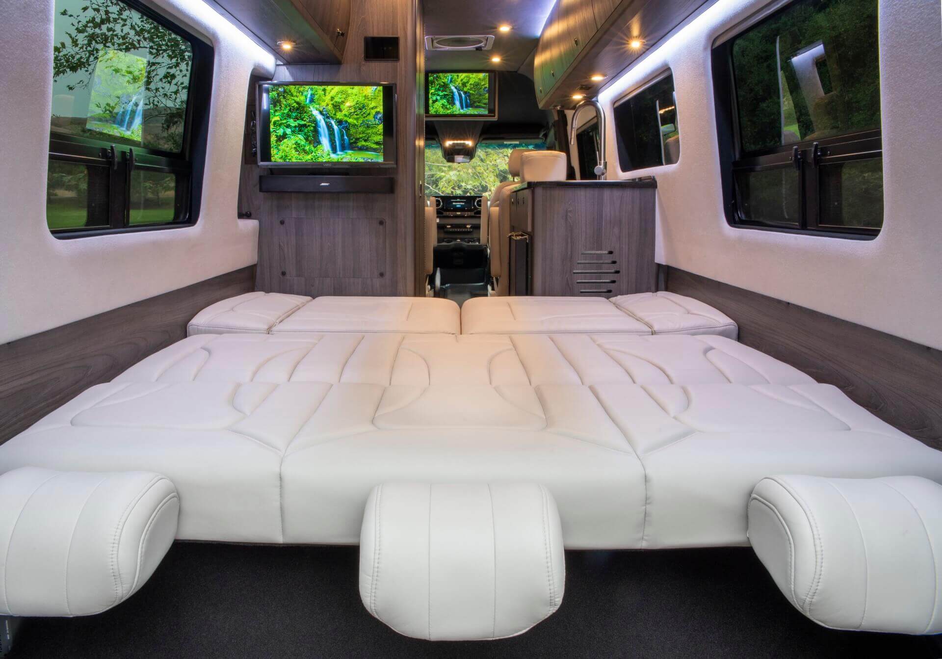 Luxury RV rental interior with a spacious, comfortable bed, dual TVs, and elegant wood paneling, perfect for your next adventure.. Grech RV Strada-ion 2024