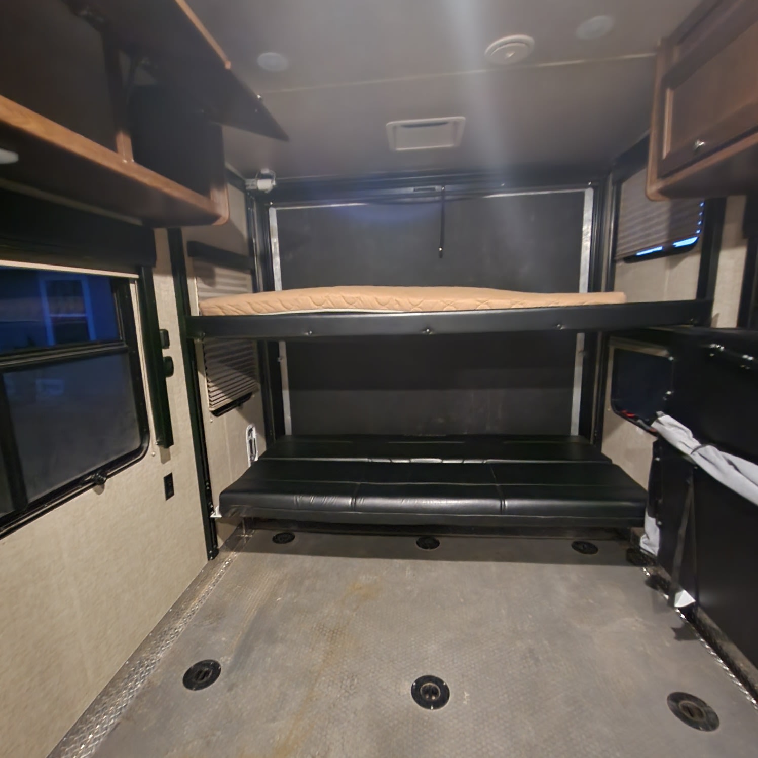 RV rental interior featuring a lower convertible sofa, upper bunk bed, and rugged flooring, ideal for adventurers.. Keystone Impact 2015