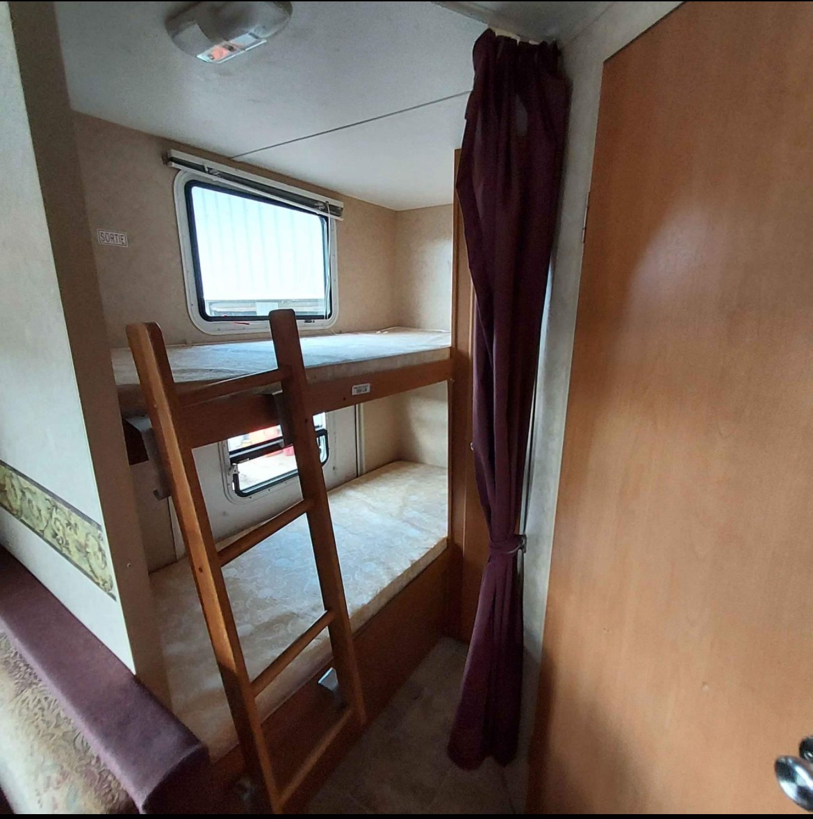 RV rental interior: Wooden bunk beds with ladder & windows offer cozy sleeping. Ideal for camper adventures.. Dutchmen Lite 2007