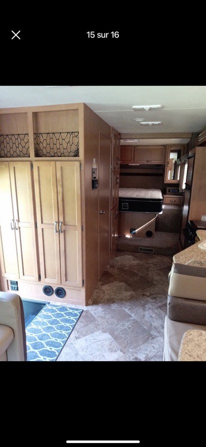 Well-appointed RV rental interior featuring light wood cabinets, a raised bed, and integrated storage.. A.C.E. A.C.E. Motorhome 2015