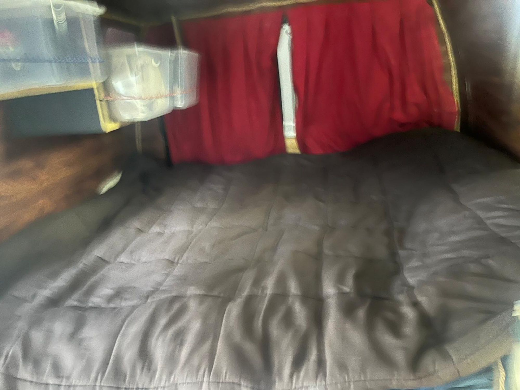 Cozy RV rental interior with a comfortable bed, clear storage bins, and red privacy curtains.. Ford Ford E350 2009
