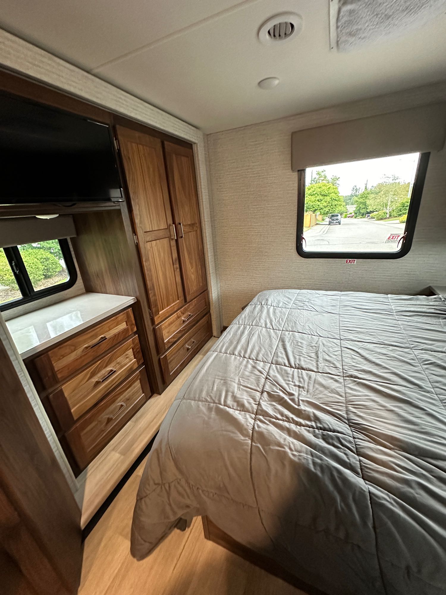 Inside an RV rental: a cozy bedroom with a large bed, wooden cabinets, TV, and window views.. Winnebago Minnie Winnie 2021