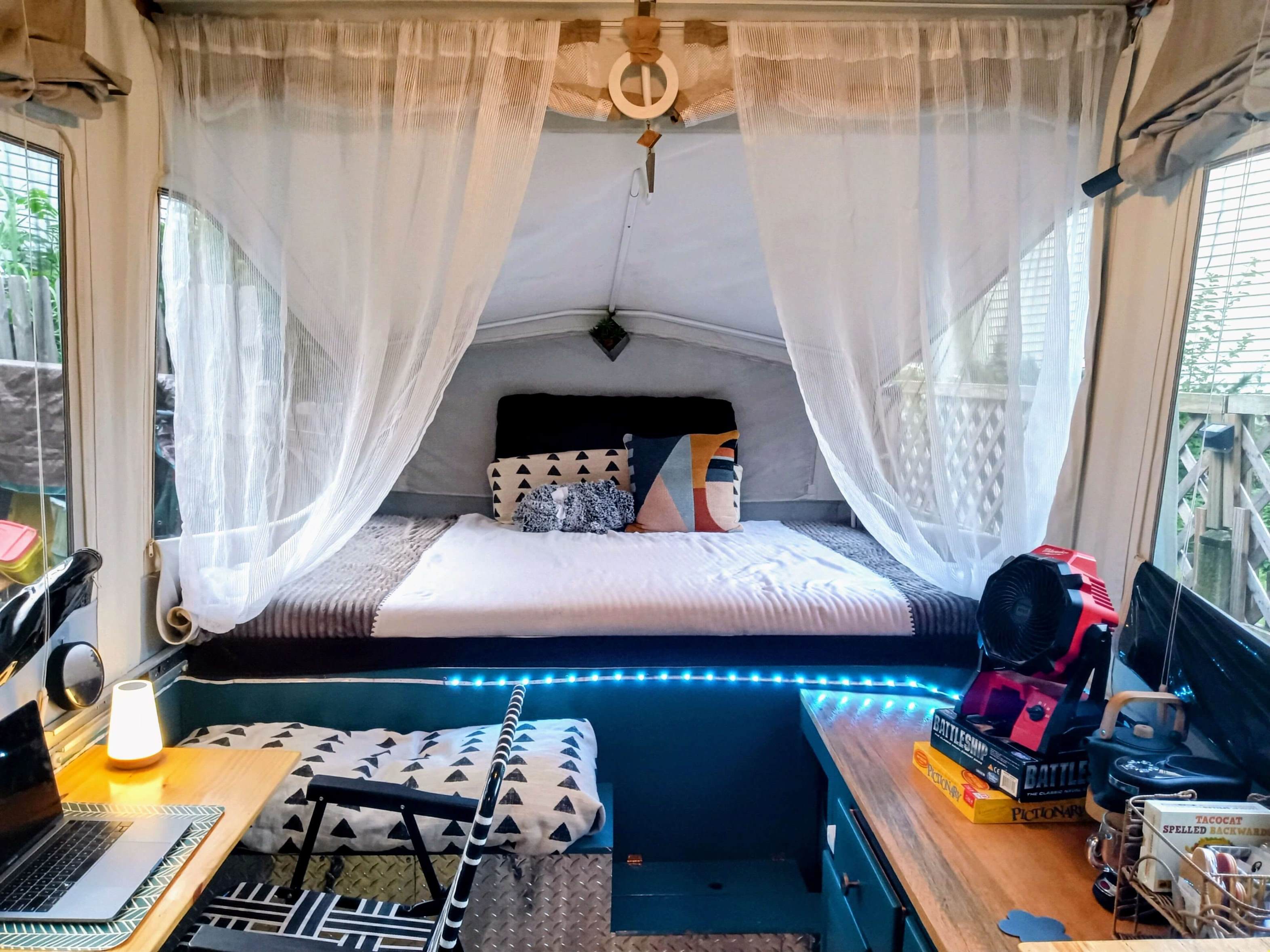This cozy pop-up camper interior, perfect for an rv rental, boasts a comfy bed, workspace, and ambient blue LEDs.. Jayco Jay 2010
