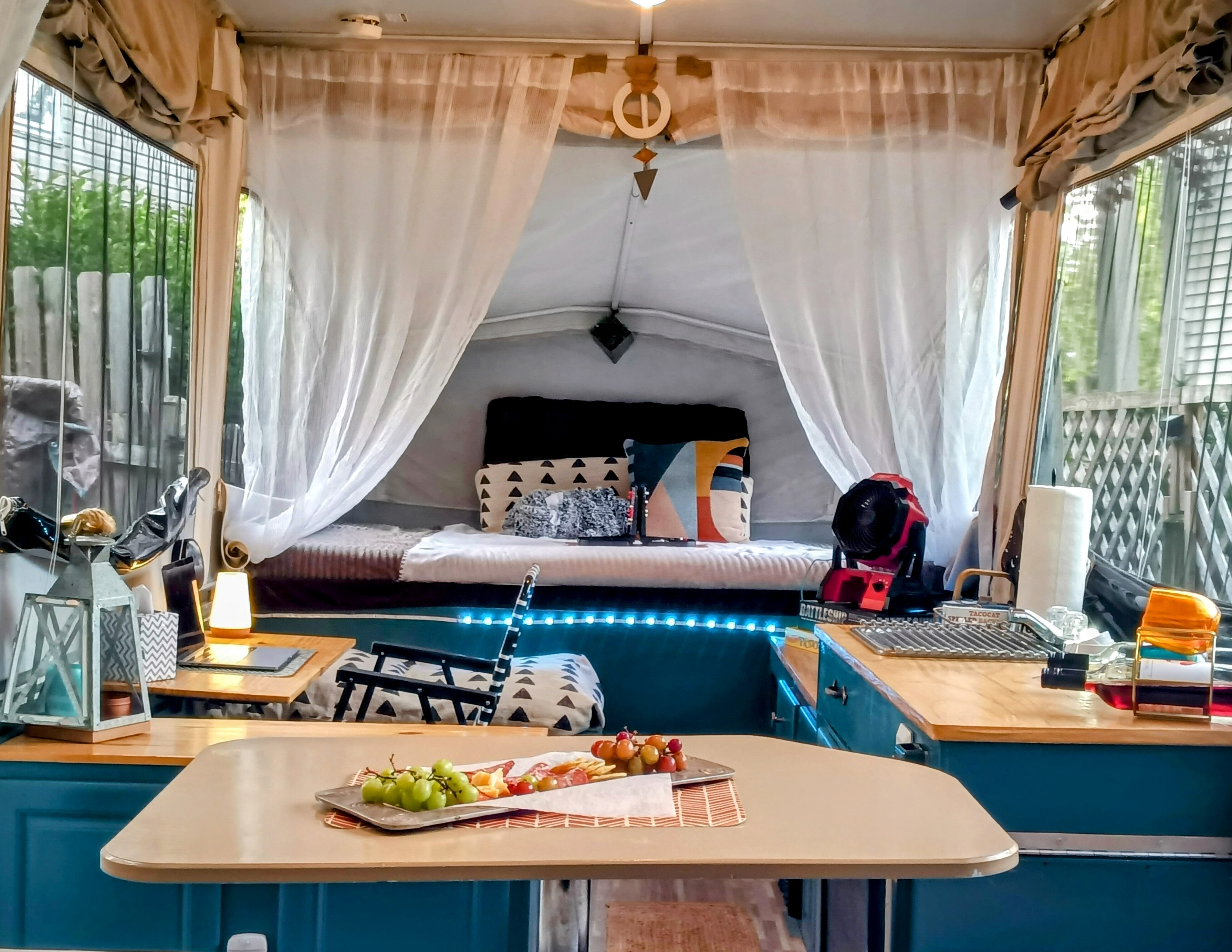 Relaxing RV rental interior: bed, cozy curtains, and a delicious snack spread on the dining table, perfect for a getaway.. Jayco Jay 2010