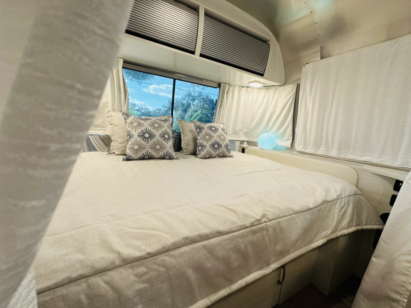 Spacious RV rental bedroom with a comfy bed & scenic window views of blue sky. Ideal for road trip adventures!. Airstream Bambi 2022
