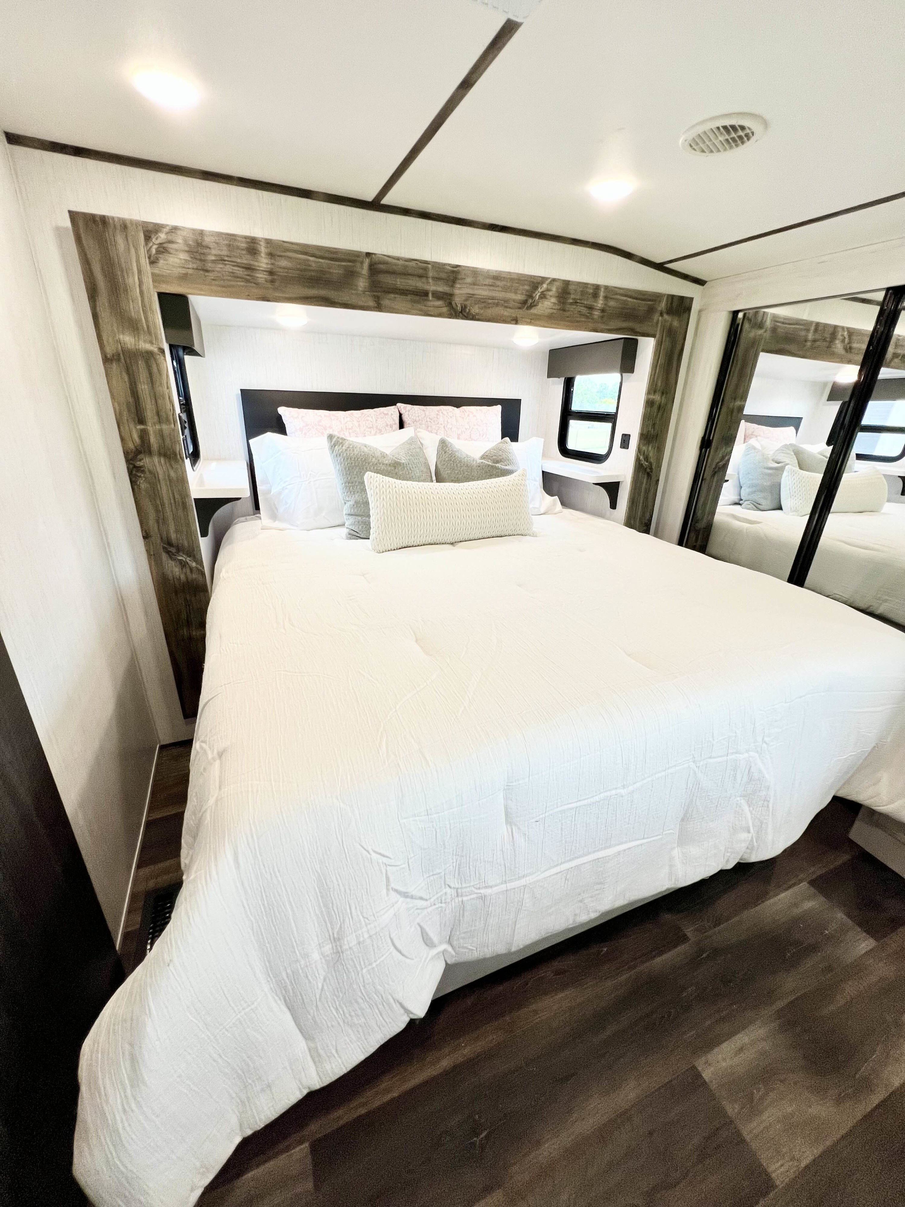 Spacious RV rental bedroom with cozy bed, rustic wood accents, and bright lighting. Perfect for travel comfort.. Heartland RVs Bighorn Traveler 2022