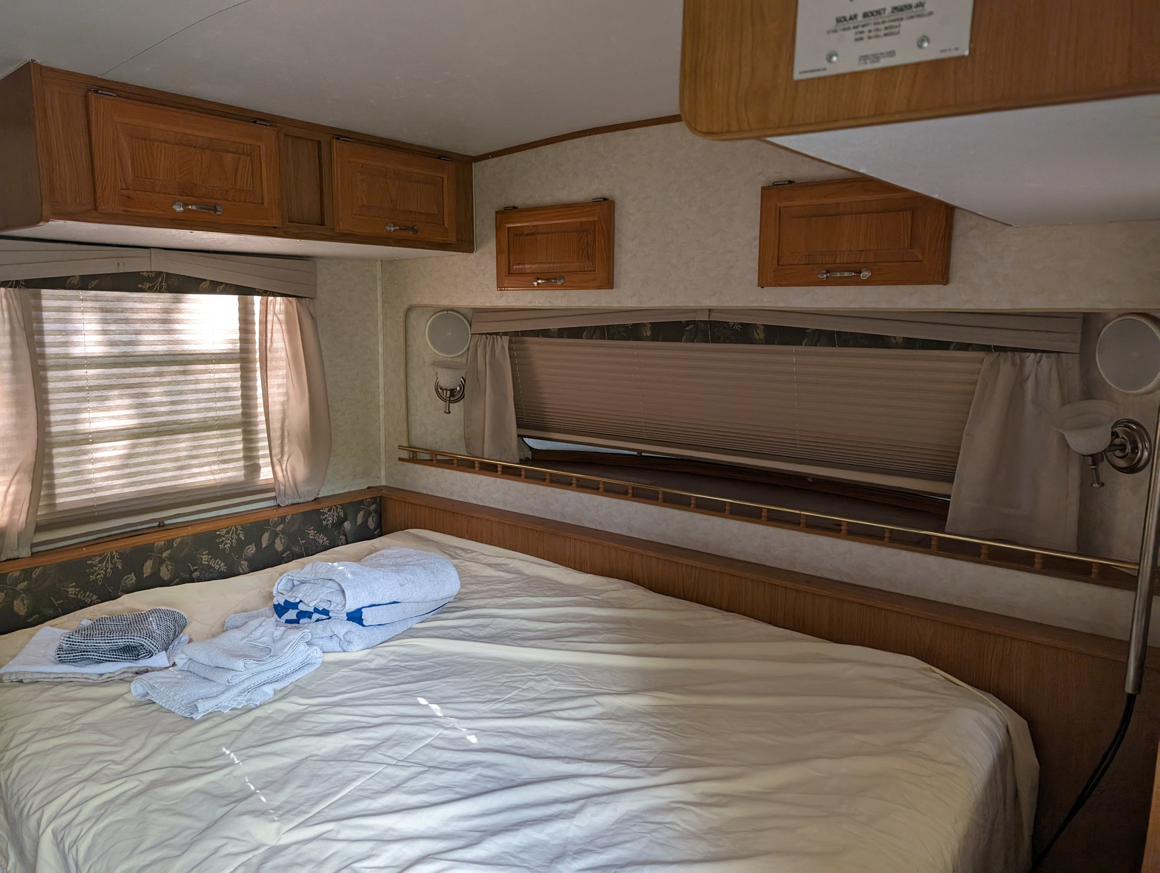 Cozy RV rental bedroom featuring a bed, wood cabinets, and large windows with blinds.. Hi Lo 2307c 2007
