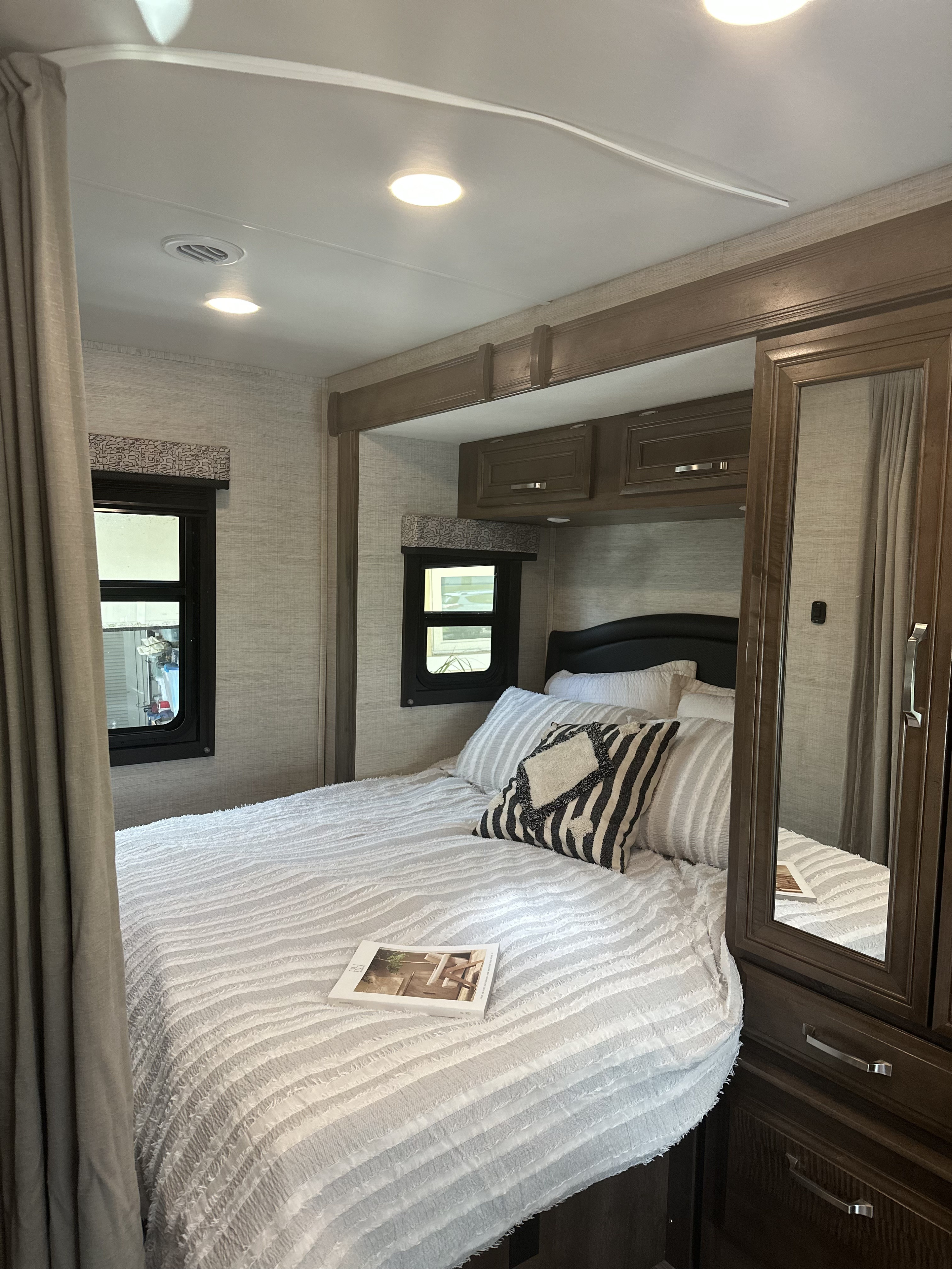 Cozy RV rental bedroom featuring a comfortable white bed, patterned pillows, small windows, and built-in storage. Ideal for travel.. Jayco Melbourne 2022