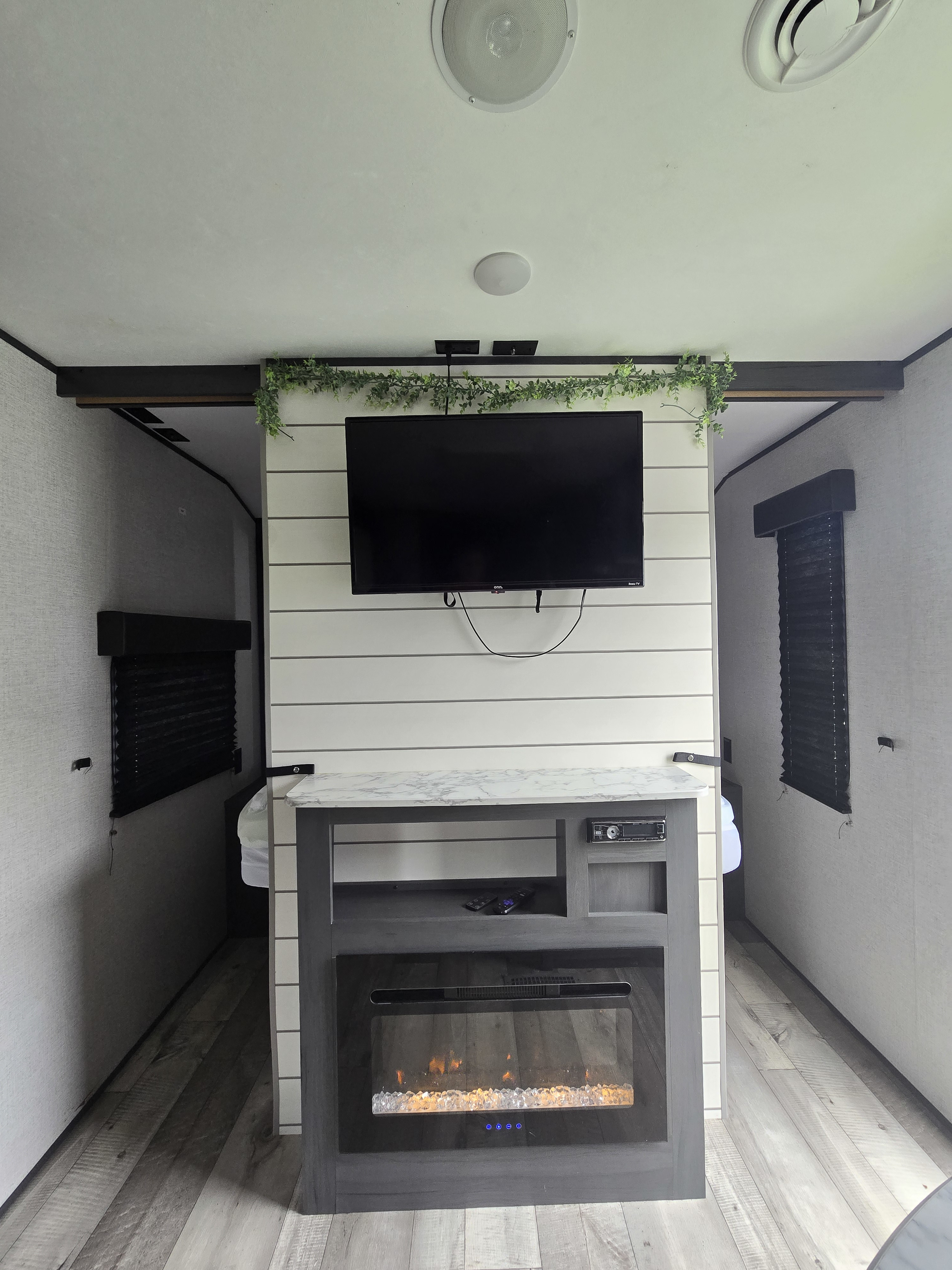 Cozy RV rental living space with TV, electric fireplace, and access to two sleeping areas. Ideal travel trailer setup.. Aspen Trail LE 2021