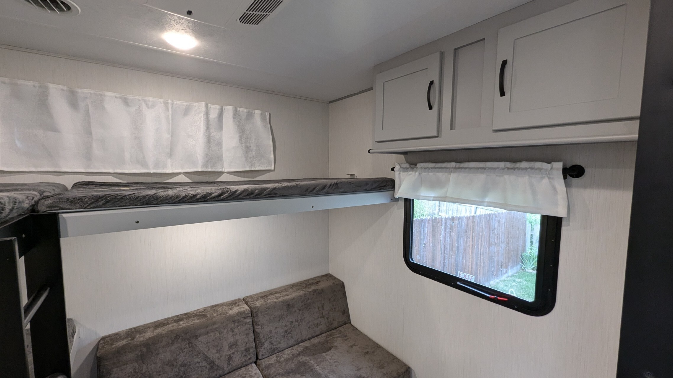 RV rental's bunkhouse features comfortable beds, a cozy sofa below, and upper cabinets with a window.. Forest River Vibe 2022