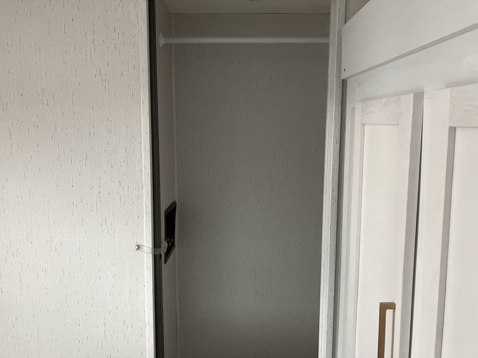 An empty, light-colored closet inside an RV rental, featuring a white hanging rod and textured walls.. Dutchmen Astoria 2022