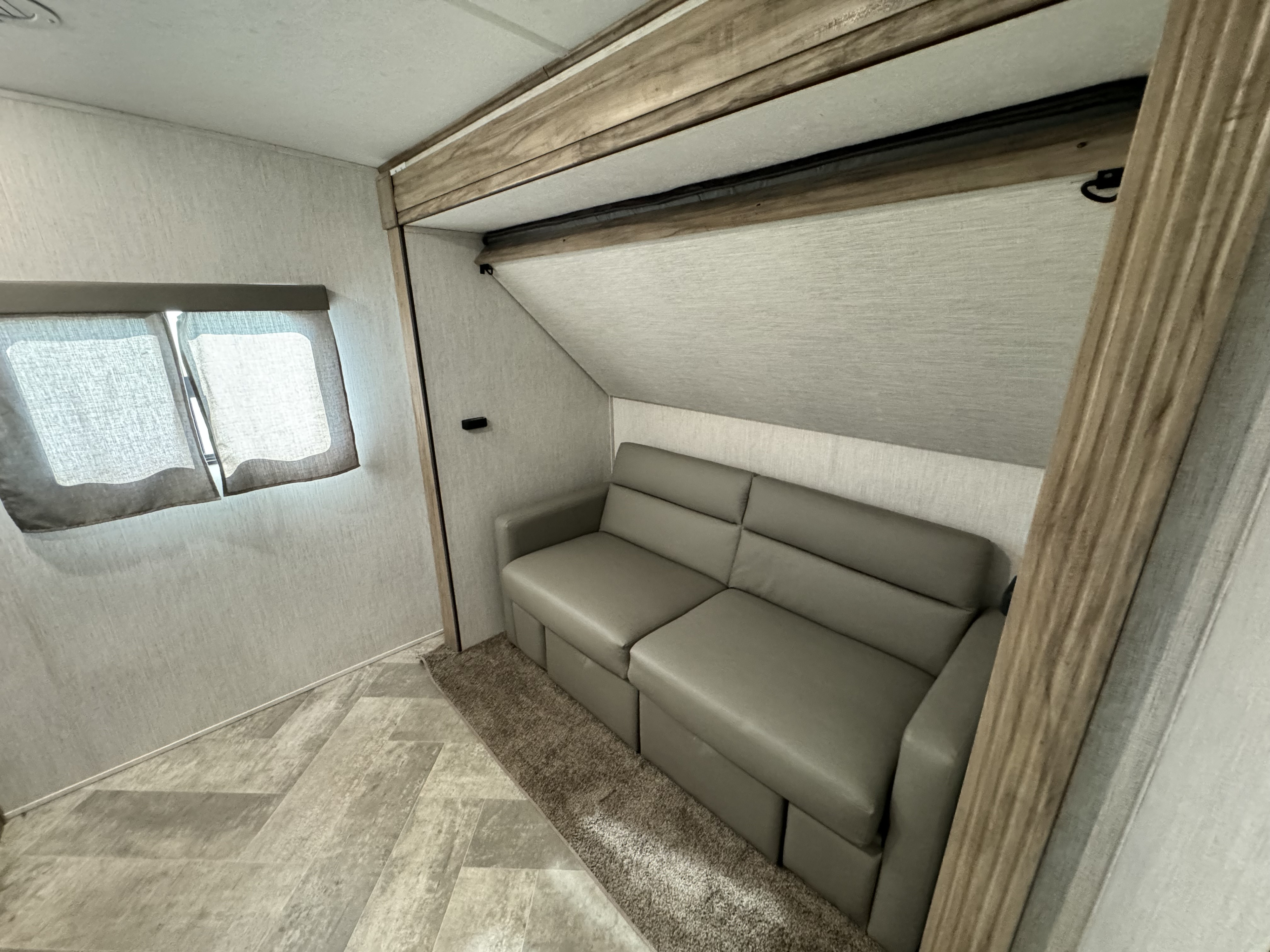 Comfortable RV rental interior with modern gray sleeper sofa, light walls, and wood-look flooring.. Forest River Palomino Solaire 2023