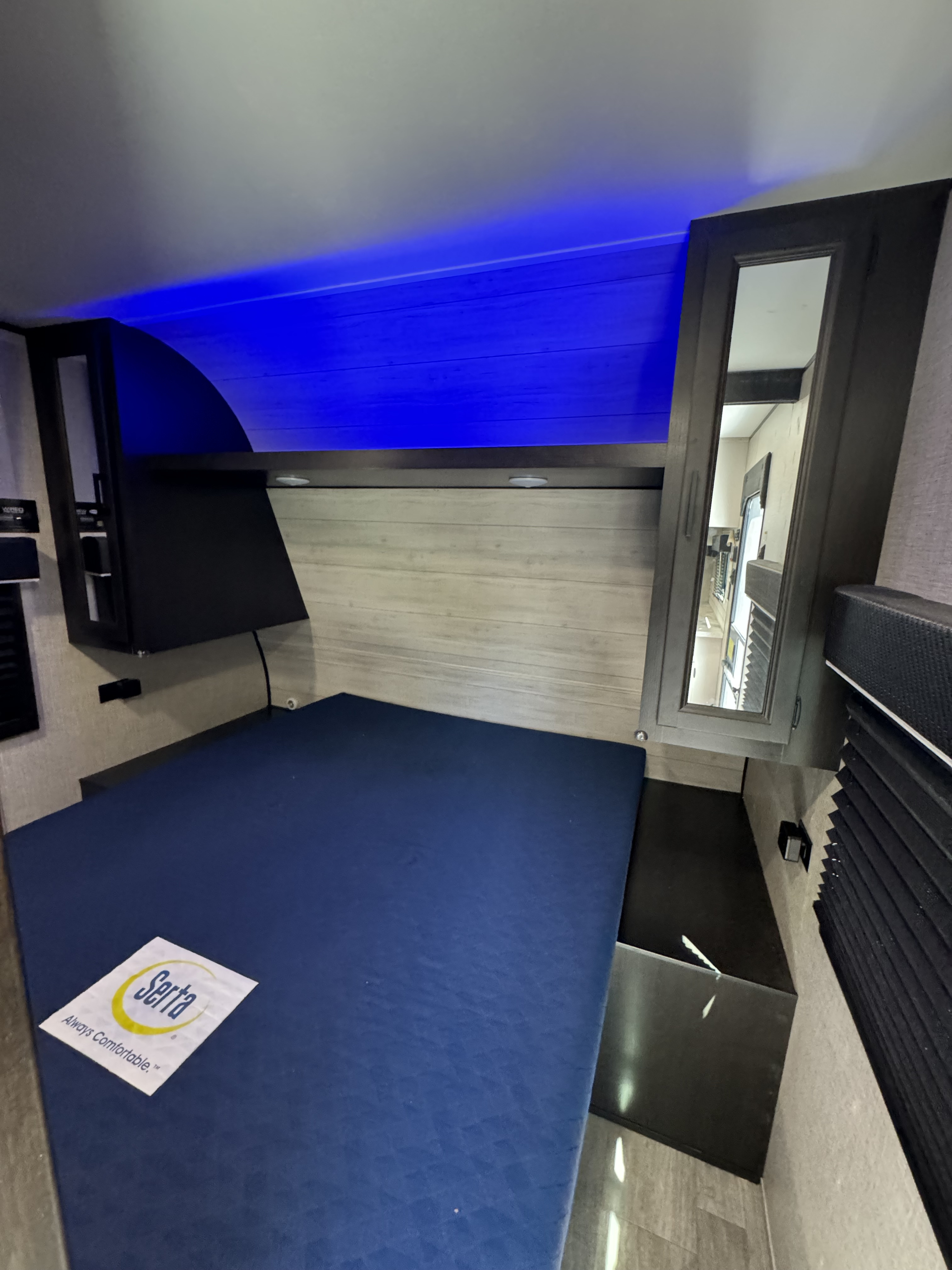 Inside a cozy RV rental bedroom featuring a blue Serta mattress, modern cabinets, and cool blue ambient lighting.. Jayco Jay Flight SLX 2022