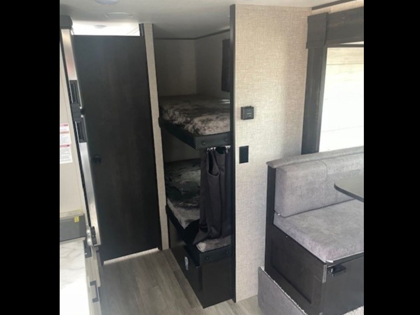 RV rental interior: bunk beds with patterned mattresses and privacy curtains, alongside a dinette. Cozy camper space.. Jayco Jay Flight SLX Baja Edition 2022