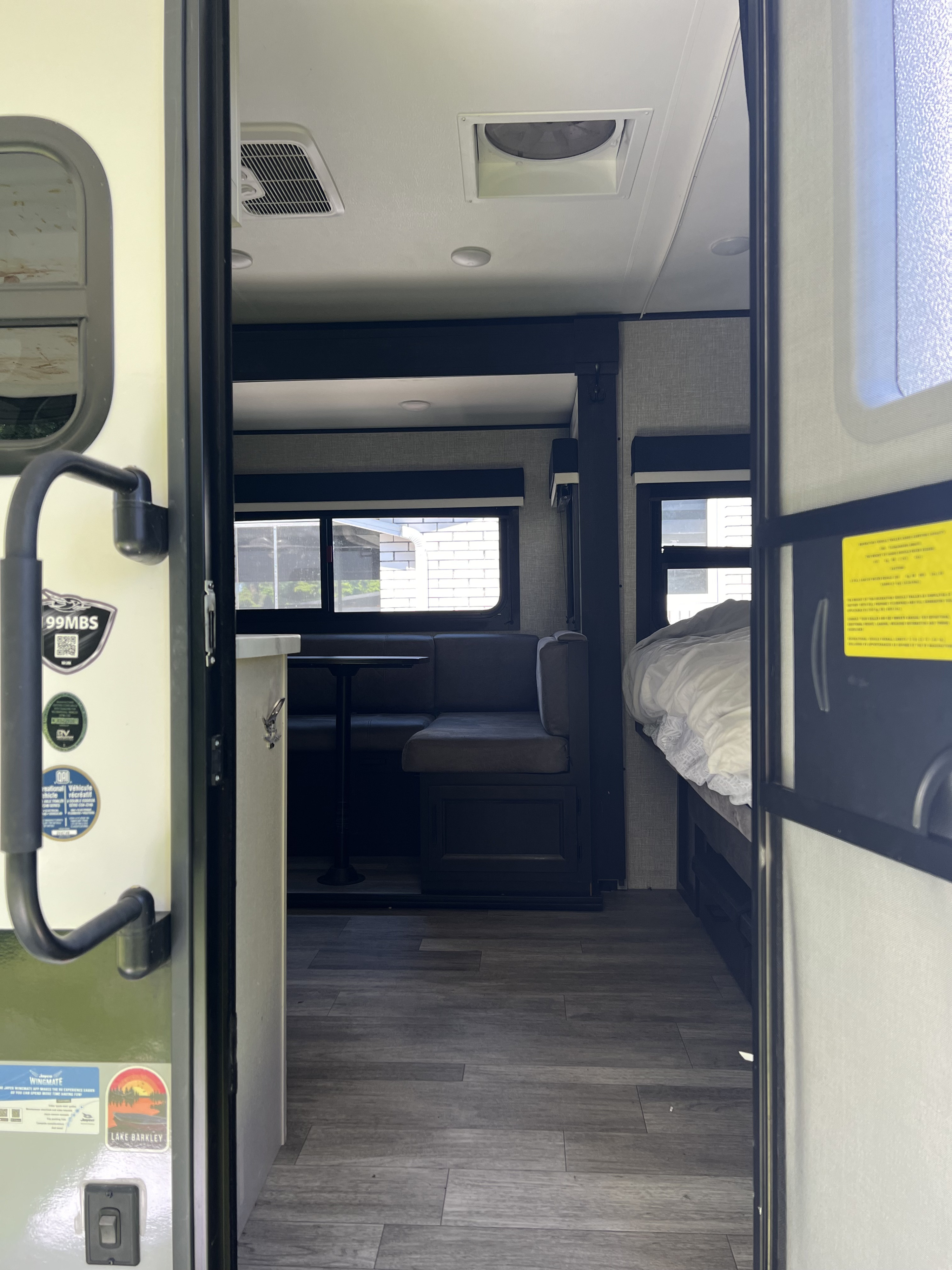 Interior of an RV rental, showing a dinette, bed, and overhead AC unit. Ideal for compact travel.. Jayco Jay Feather Micro 2022
