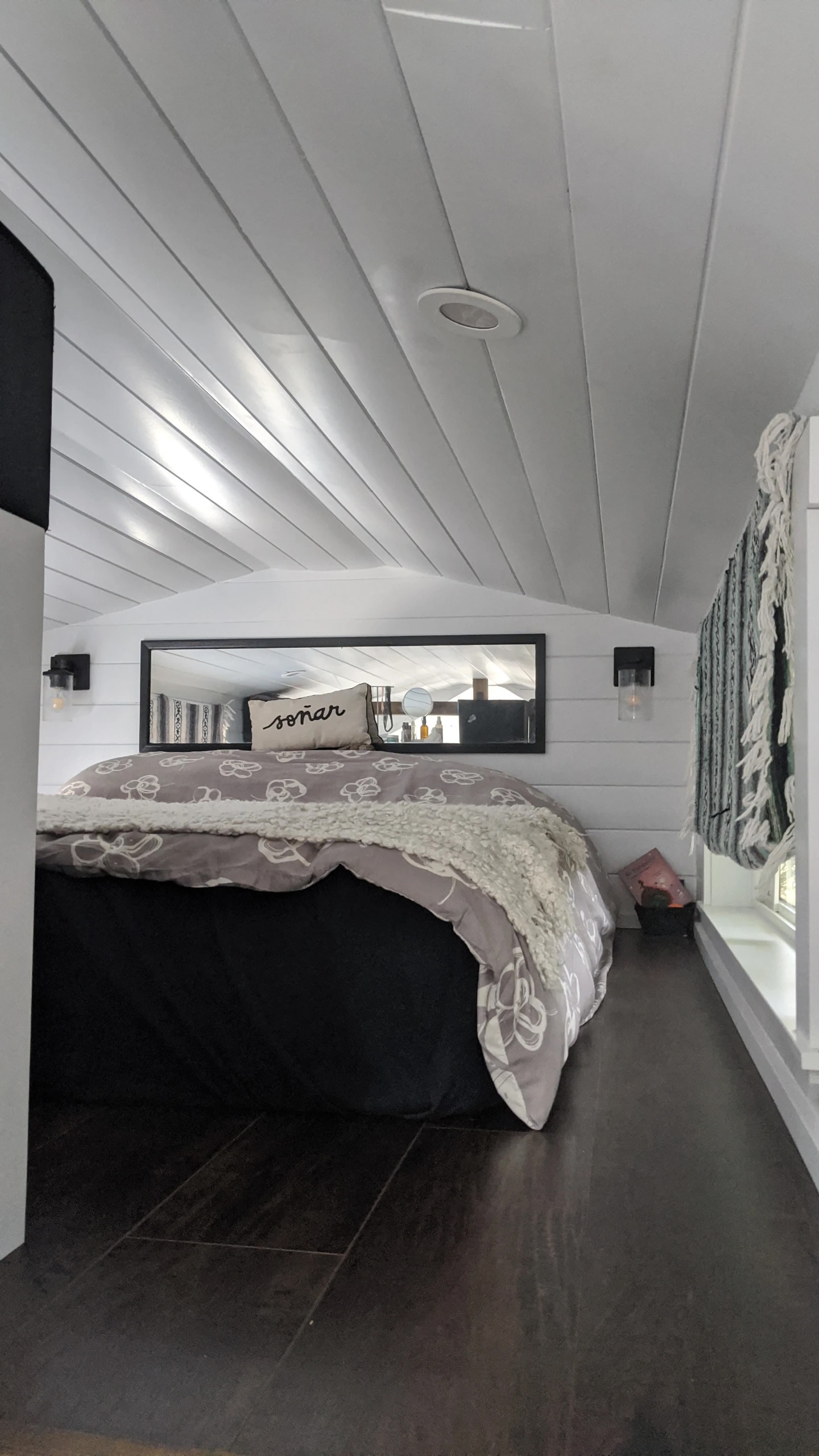 Cozy RV rental bedroom with a comfy bed, white walls & ceiling, dark floor, and mirror. Ideal tiny home interior.. Mint Tiny Homes Tiny House 2021