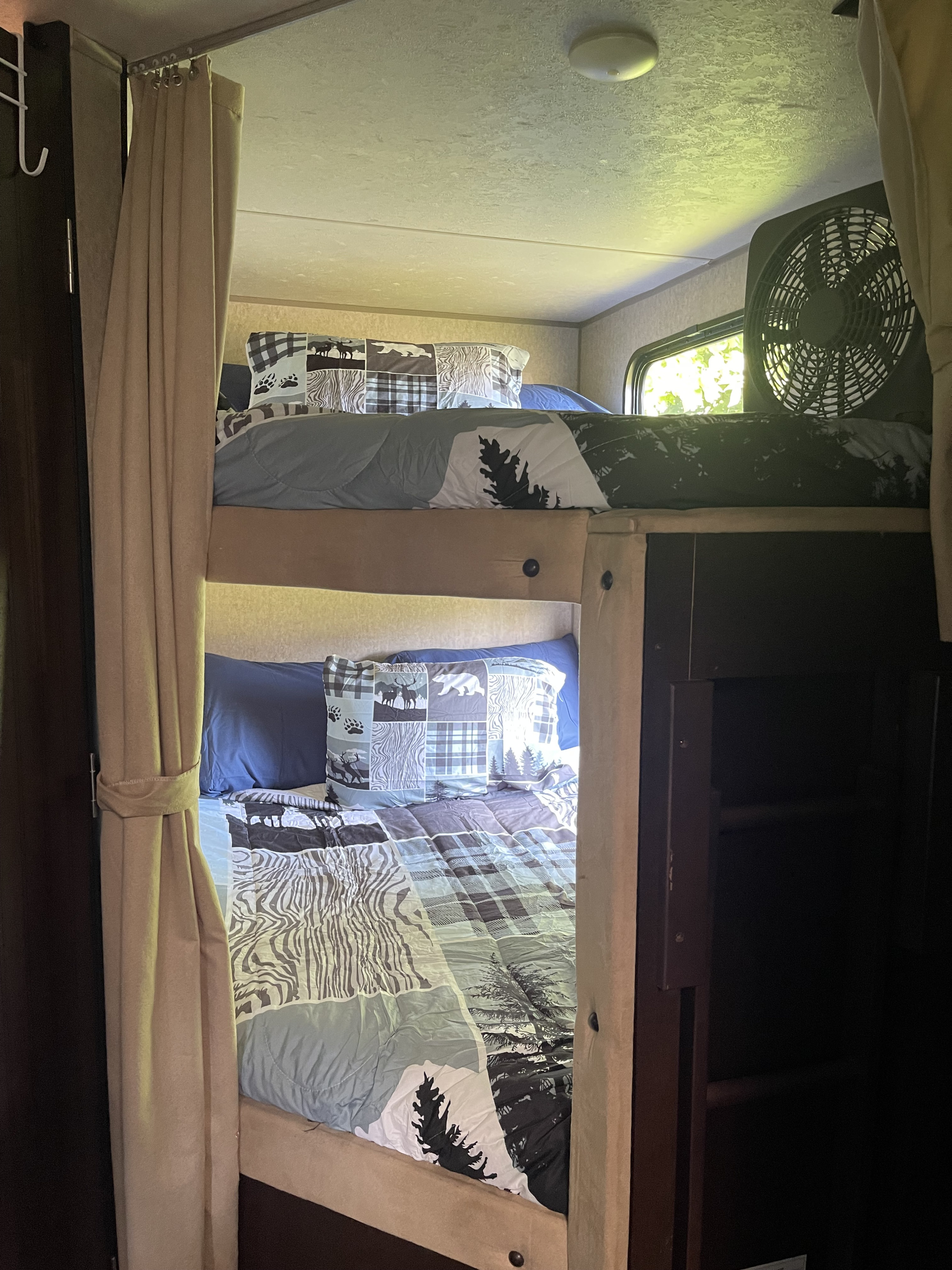 Cozy RV rental bunk beds with nature-themed bedding & fan, perfect for family adventures.. Forest River Cherokee Grey Wolf 2016