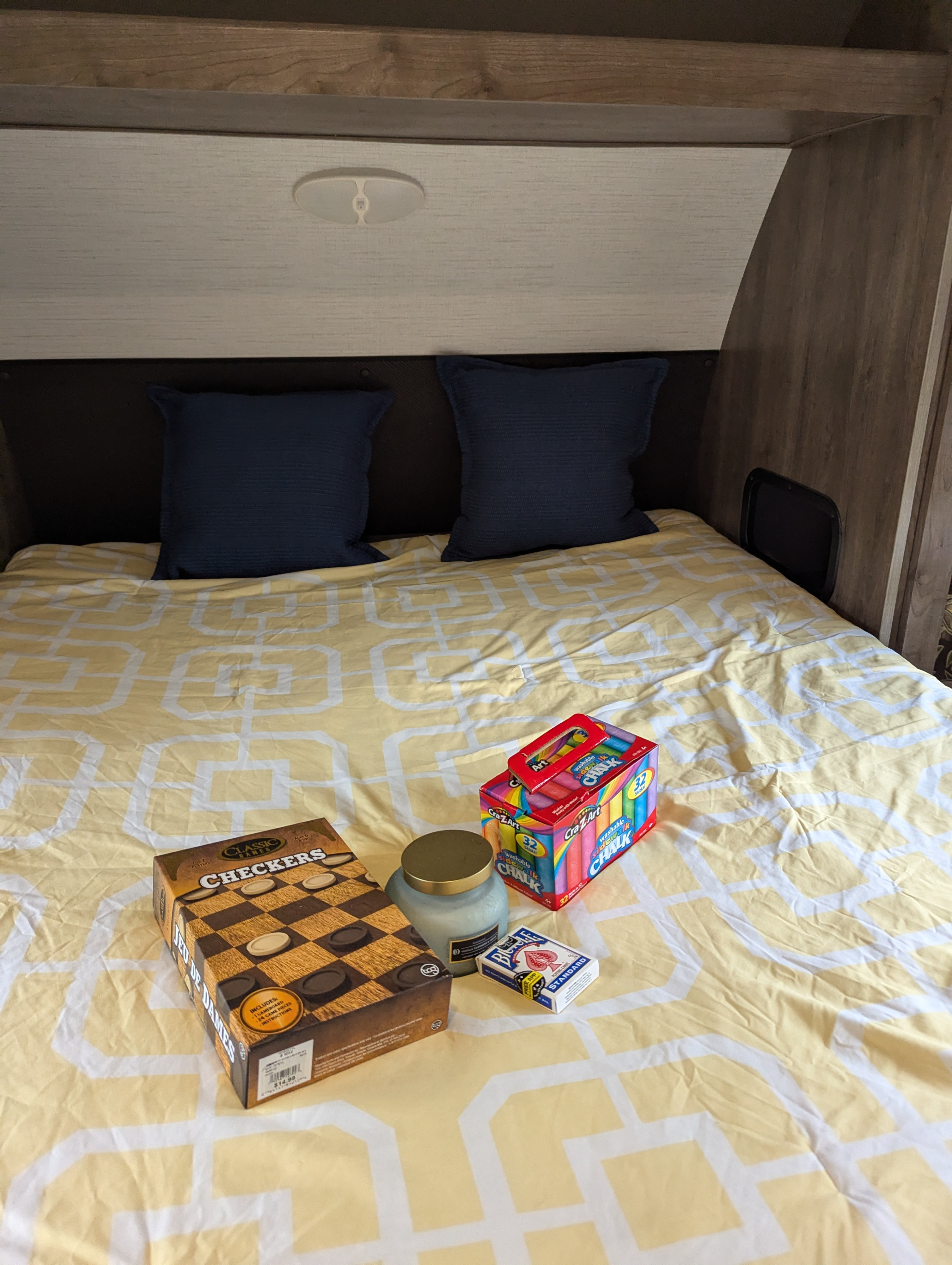 Cozy RV rental bed with games: Checkers, chalk, cards, and a candle, ready for fun and relaxation.. Heartland RVs Pioneer 2021