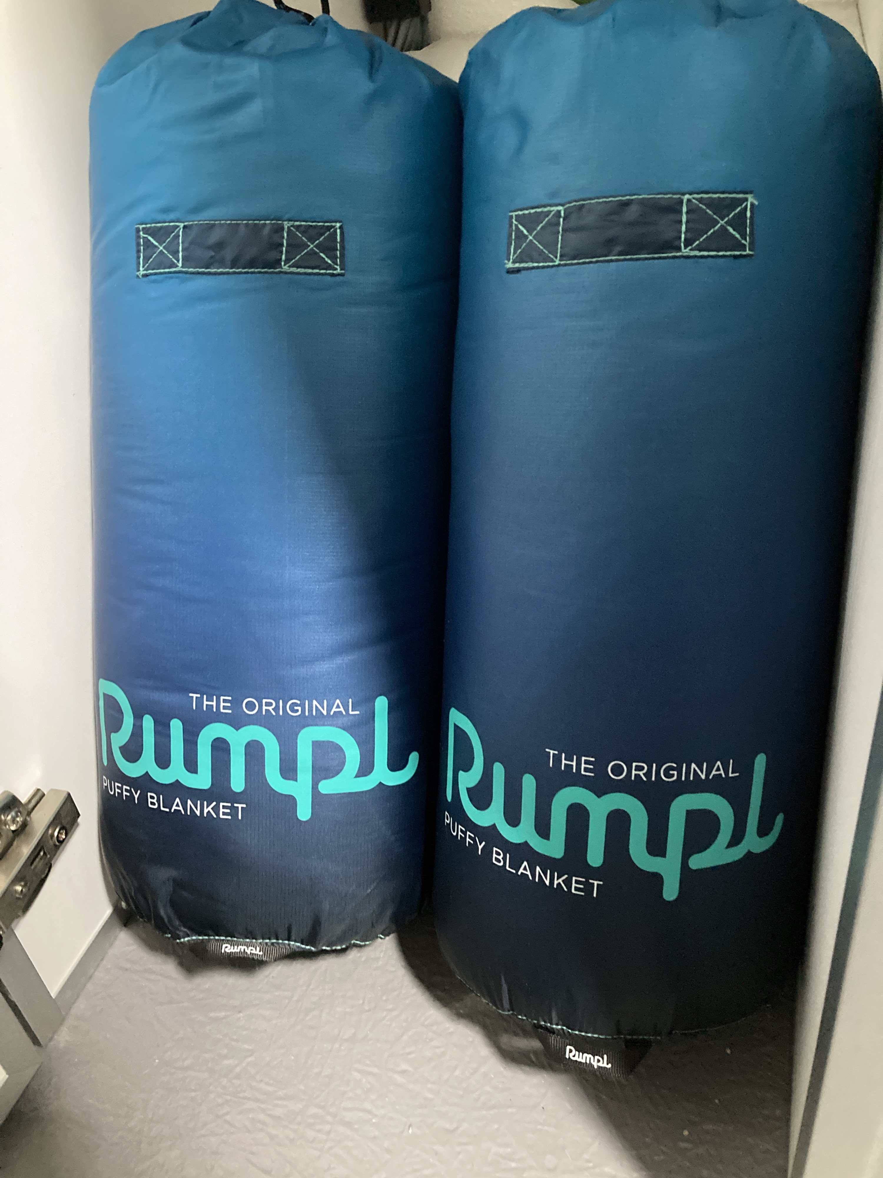 Two blue ombre Rumpl puffy blankets, ideal for an RV rental camping trip, are compactly stored.. Helio Helio Trailer 2023