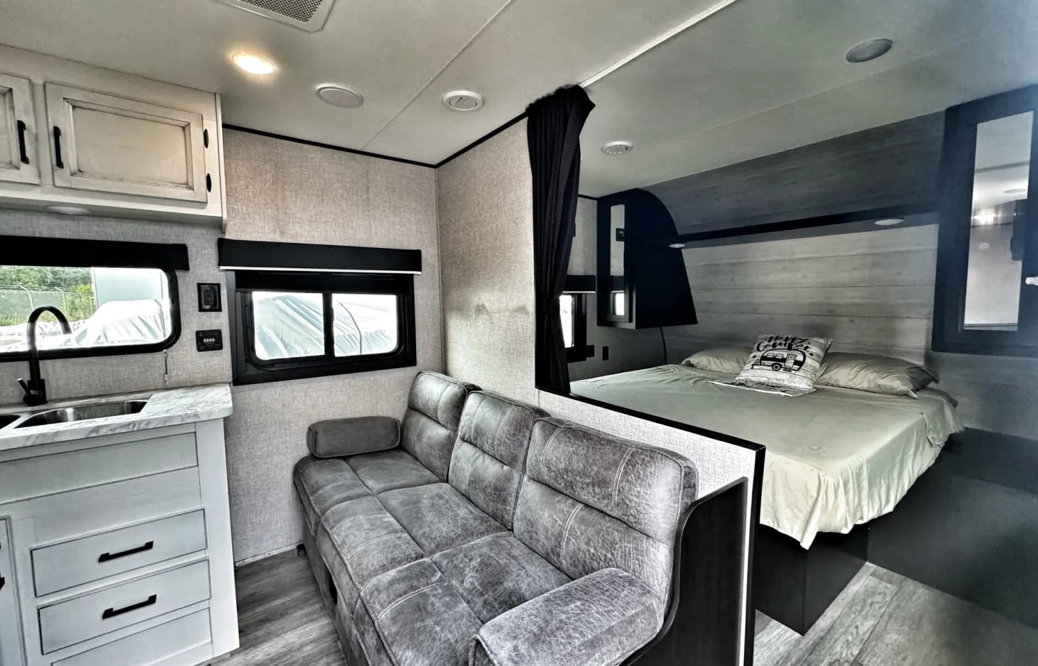 Spacious RV rental interior featuring a modern kitchenette, comfortable sofa, and a private bedroom area.. Jayco Jay Flight SLX 2022