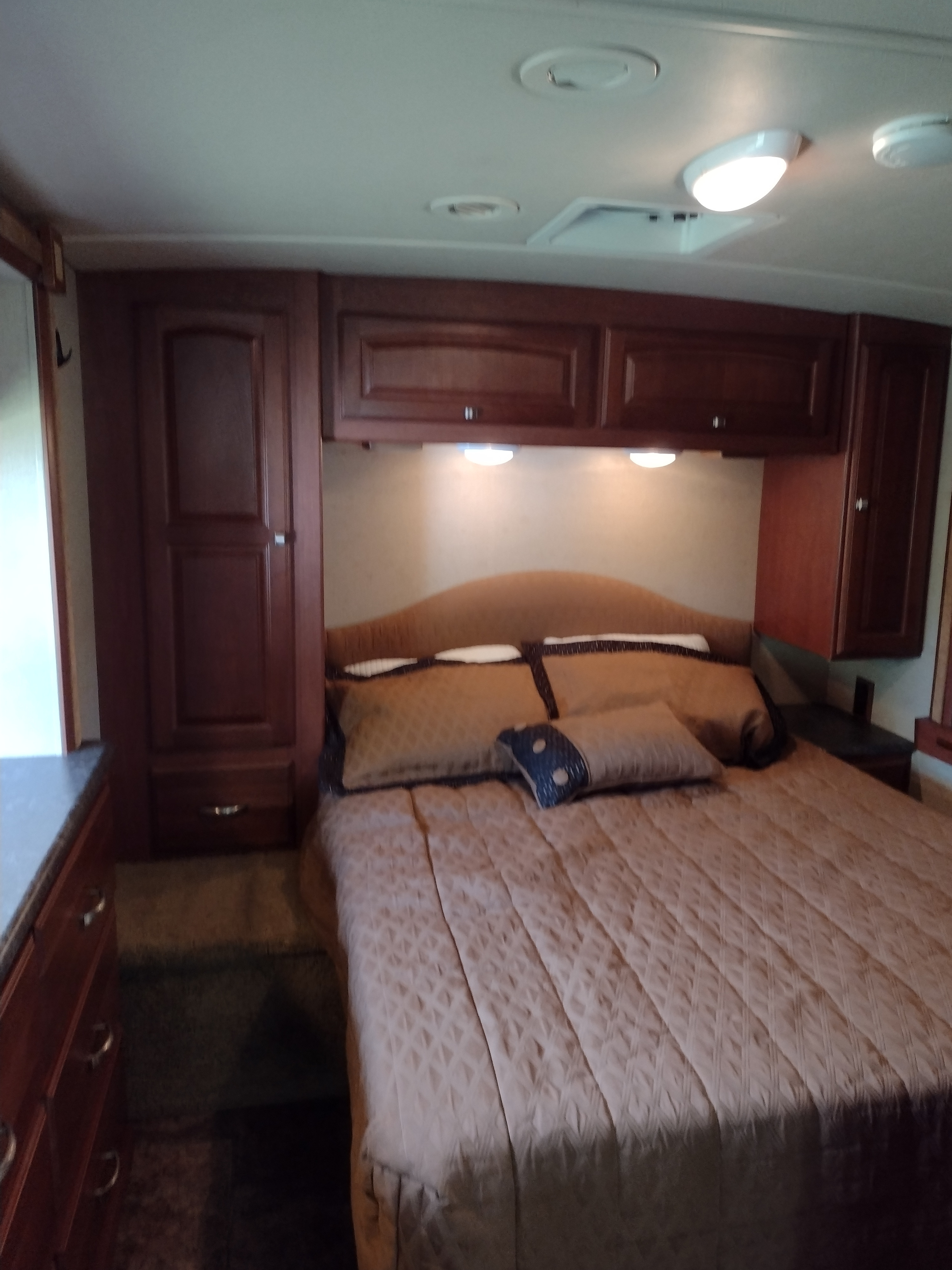 Step into comfort: A cozy RV rental bedroom featuring a full bed, overhead cabinets, and built-in storage.. Winnebago Vista 2013