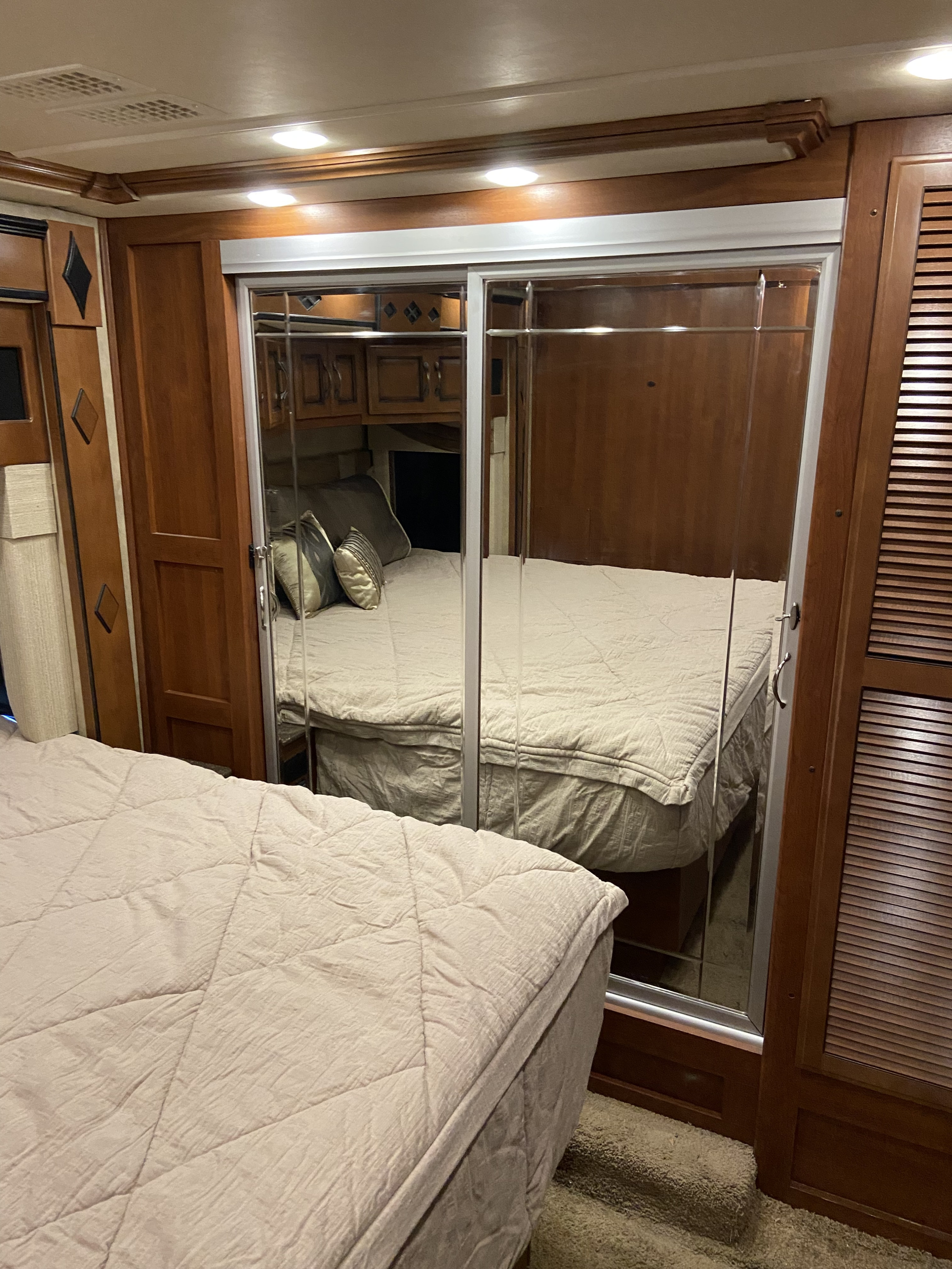 This cozy RV rental bedroom features a comfortable bed in the foreground and a mirrored closet reflecting another sleeping area.. Fleetwood Other 2015