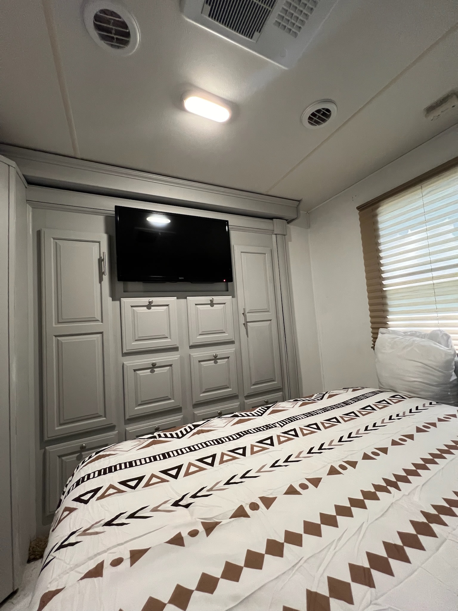 Cozy RV rental bedroom with built-in storage, TV, and patterned bedding. Perfect for comfortable travel.. Georgetown Georgetown Motorhome 2016