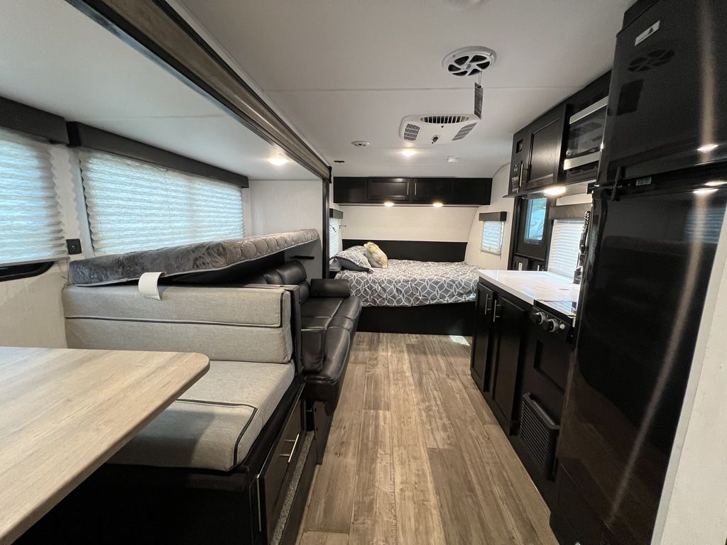 Modern RV rental interior: kitchen with fridge, living area with sofa, dinette with convertible bed, and back bedroom.. Forest River Cherokee Wolf Pup Black Label 2022