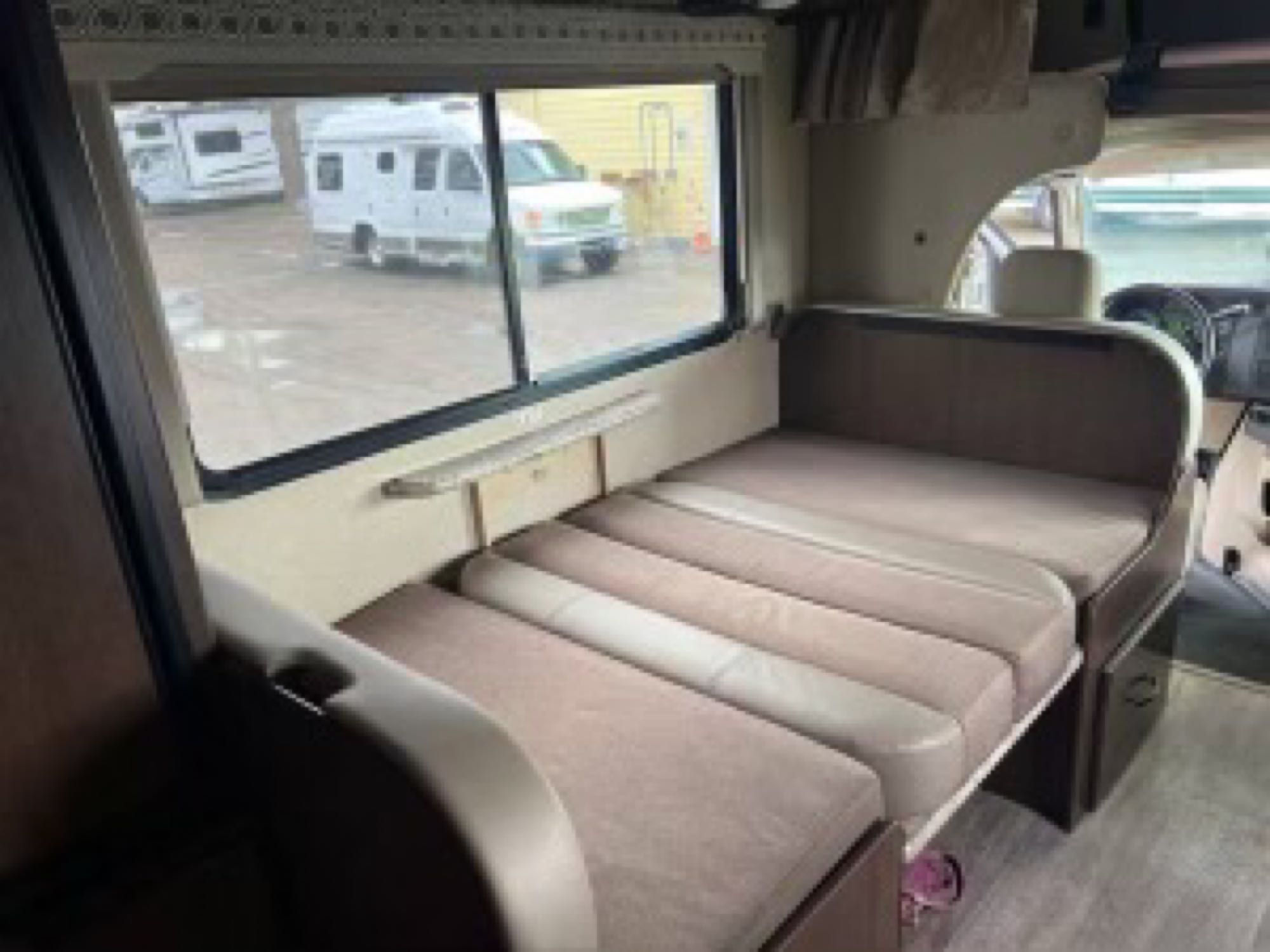 Relax in this RV rental's versatile dinette, easily converting to a bed, with an exterior view of a camper lot.. Thor Motor Coach Four Winds 2018