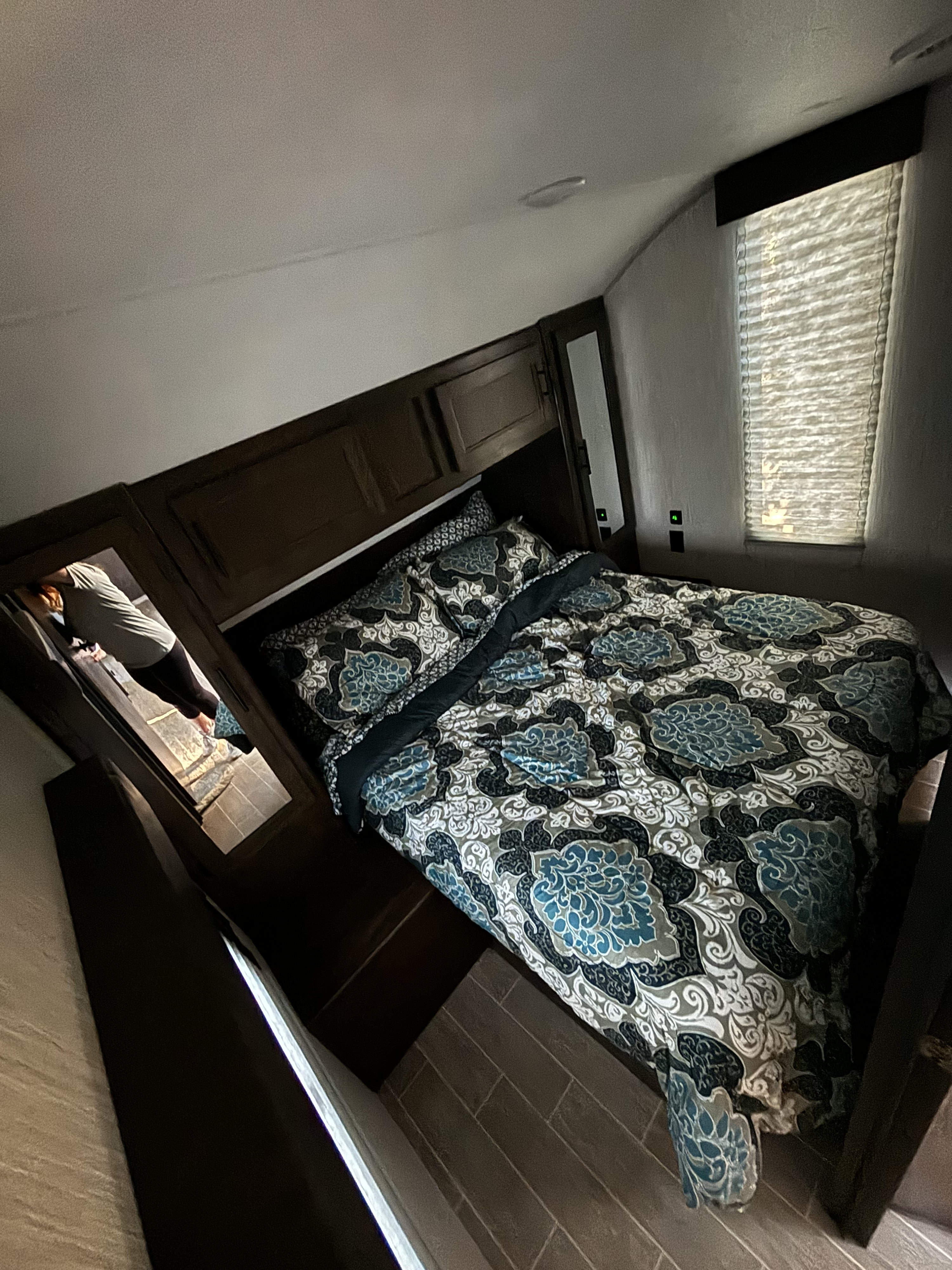 Cozy RV rental bedroom with patterned bedding, overhead storage, and a mirrored closet, offering compact comfort.. Forest River Cherokee 2021