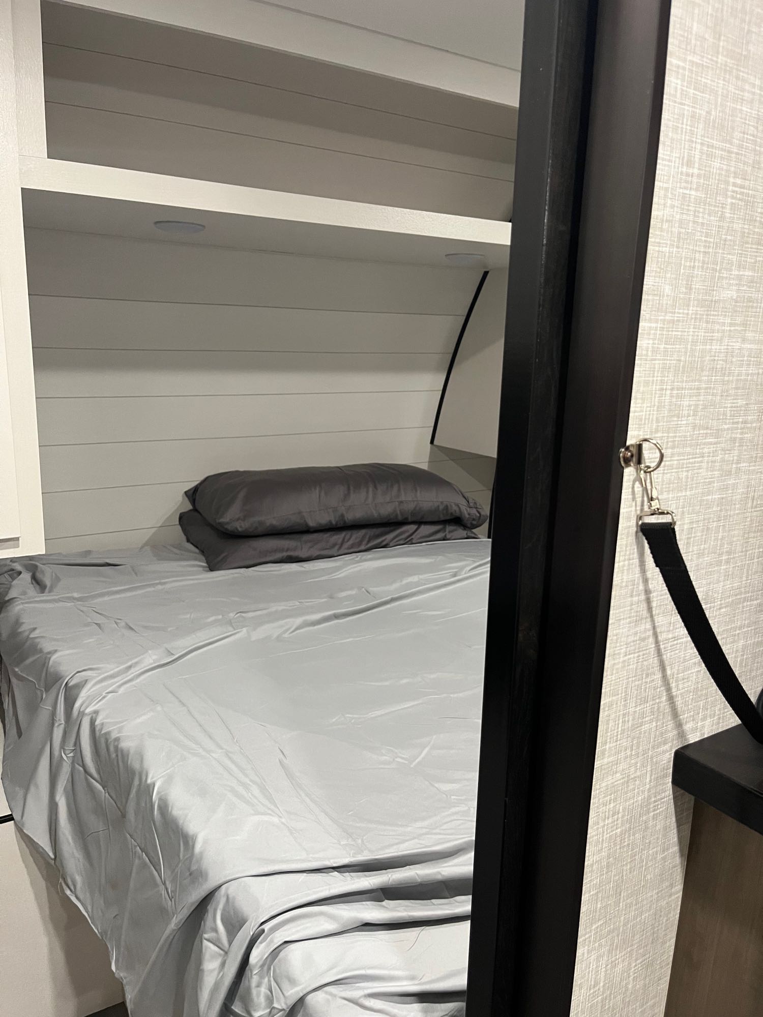 RV rental interior: A compact bunk bed with light gray sheets, pillows, and a built-in shelf for comfort.. Jayco JayFlight SLX 2024