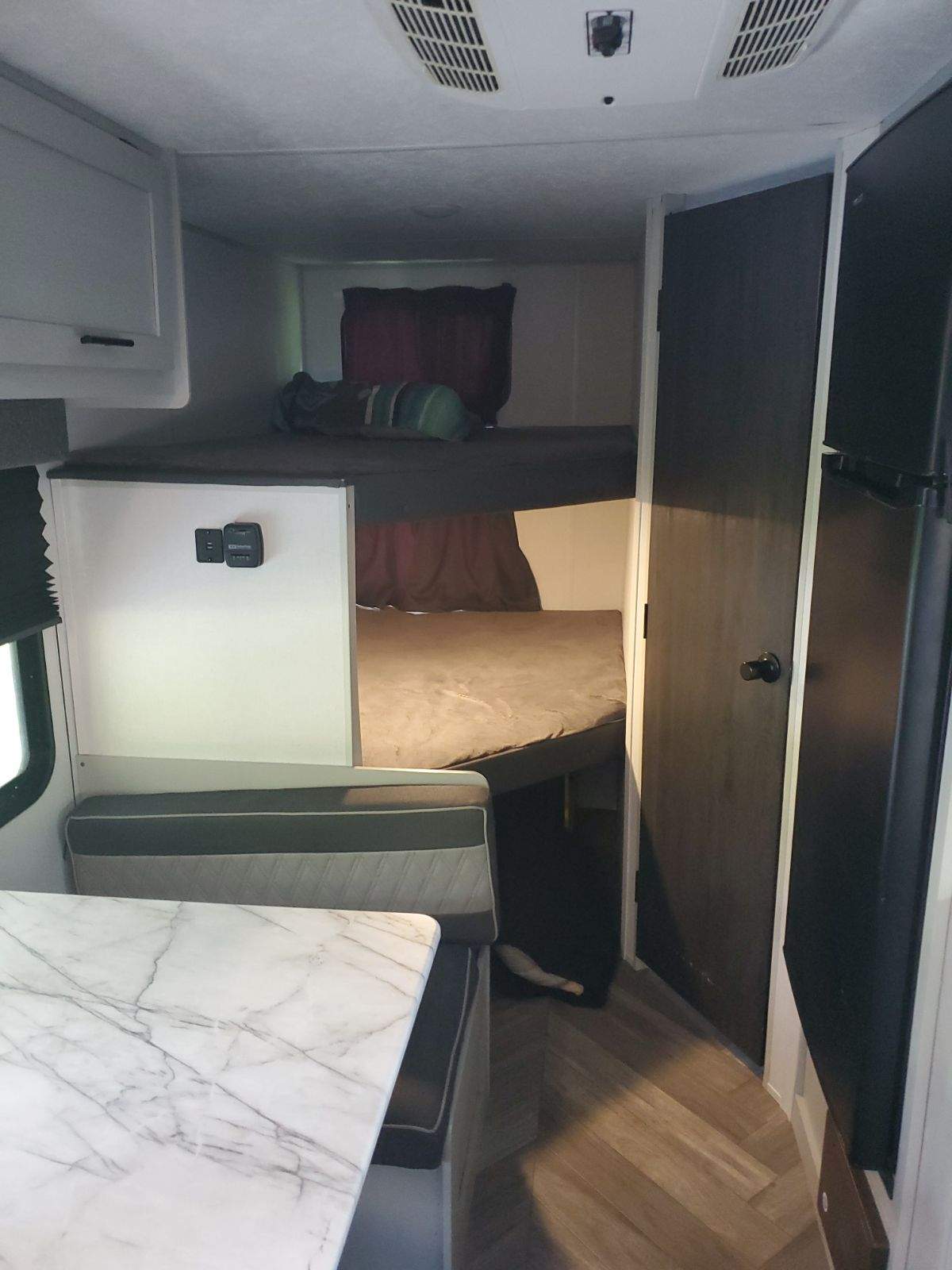 This cozy RV rental interior showcases bunk beds, a dinette, and compact kitchen space, perfect for family adventures.. Forest River Salem FSX 2021
