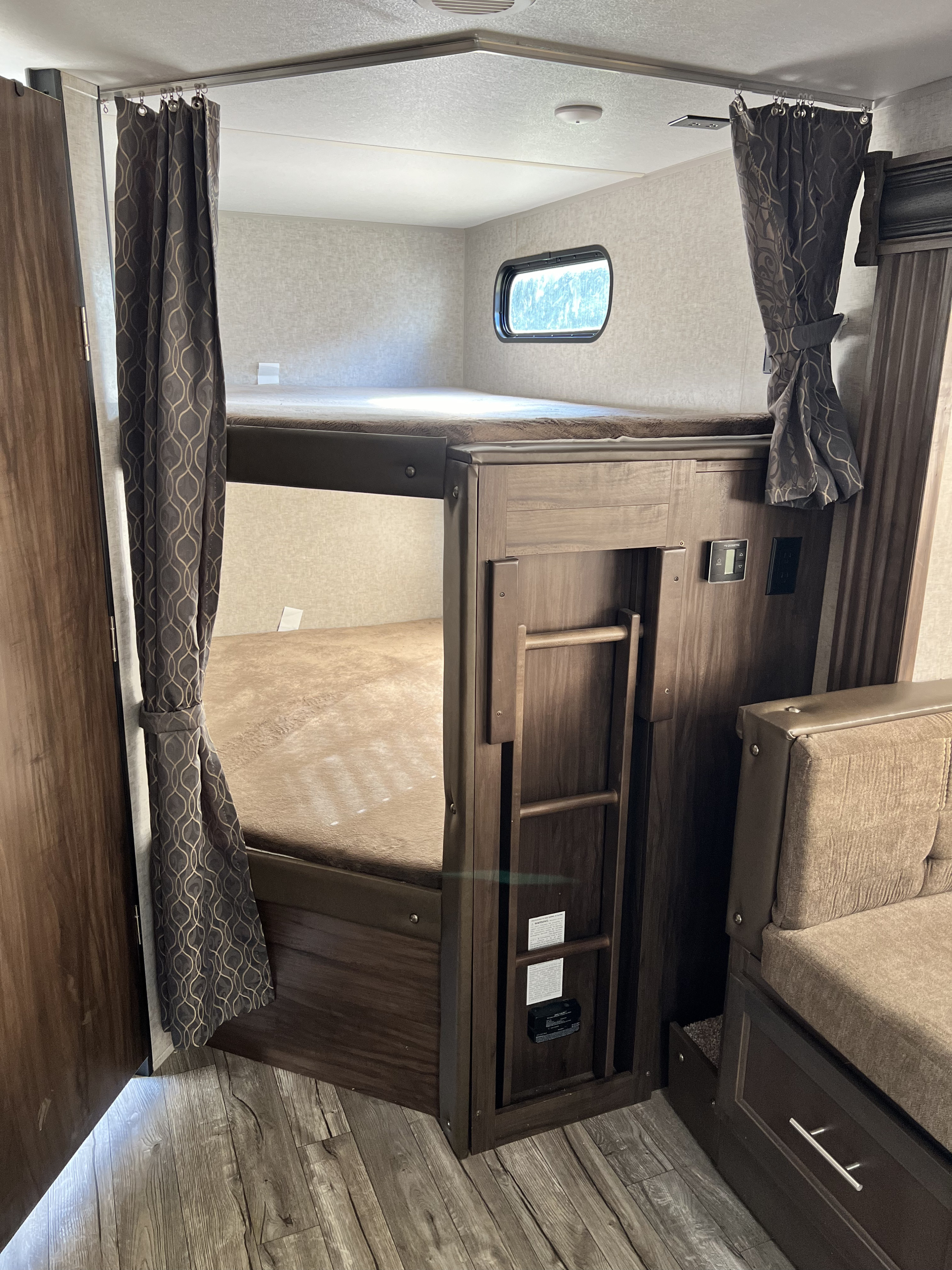RV rental interior: cozy bunk beds with privacy curtains, ladder, window, and a control panel for comfortable stays.. Forest River Cherokee Grey Wolf 2019