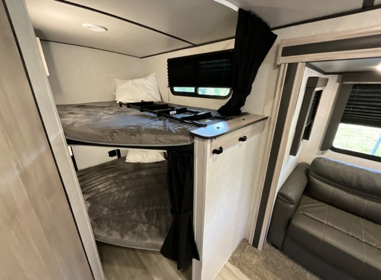 Modern RV rental interior with bunk beds, a ladder for the top bed, and a comfortable grey sofa.. Coachmen 2021 Coachman Sprinter Campfire Edition 2021