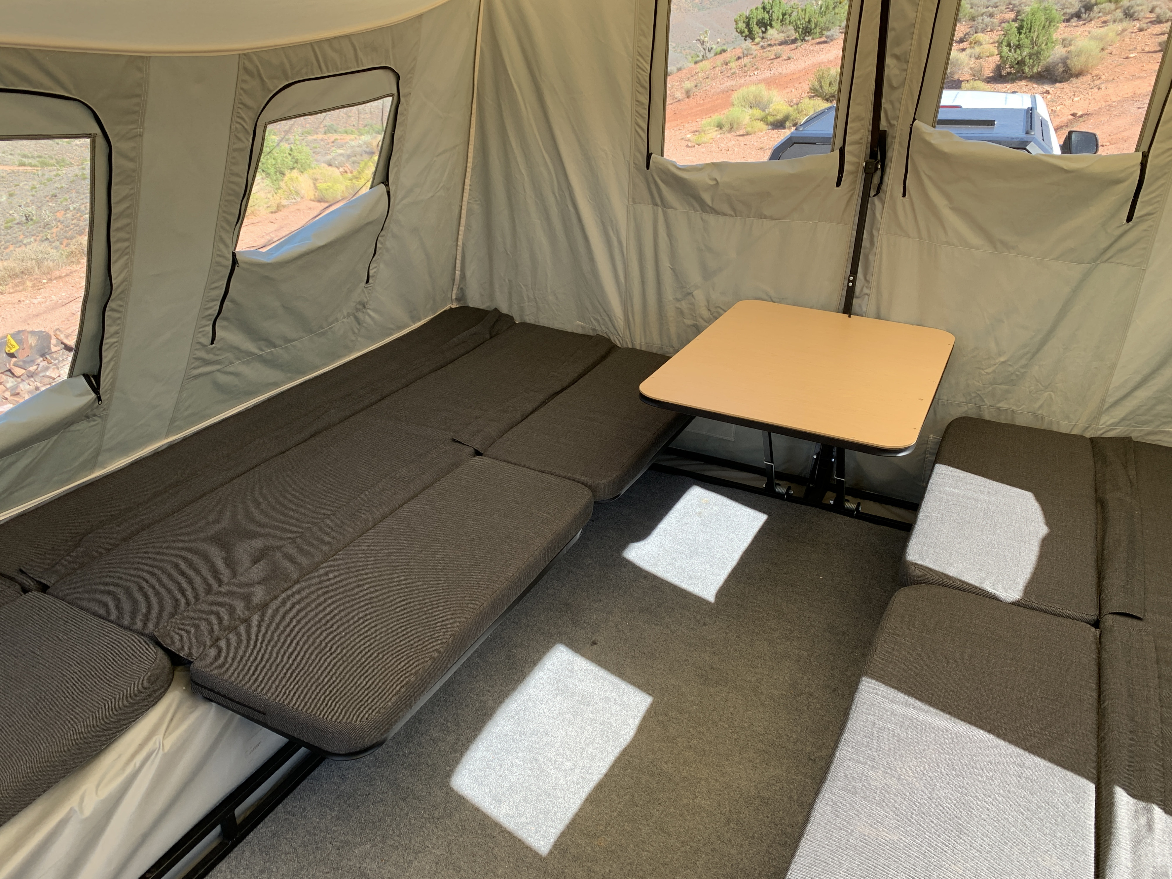 Cozy RV rental interior with modular seating, a dining table, and large windows revealing scenic desert landscapes.. Jumping Jack Jumping Jack 6x12 12' Tent Mid Blackout 2022