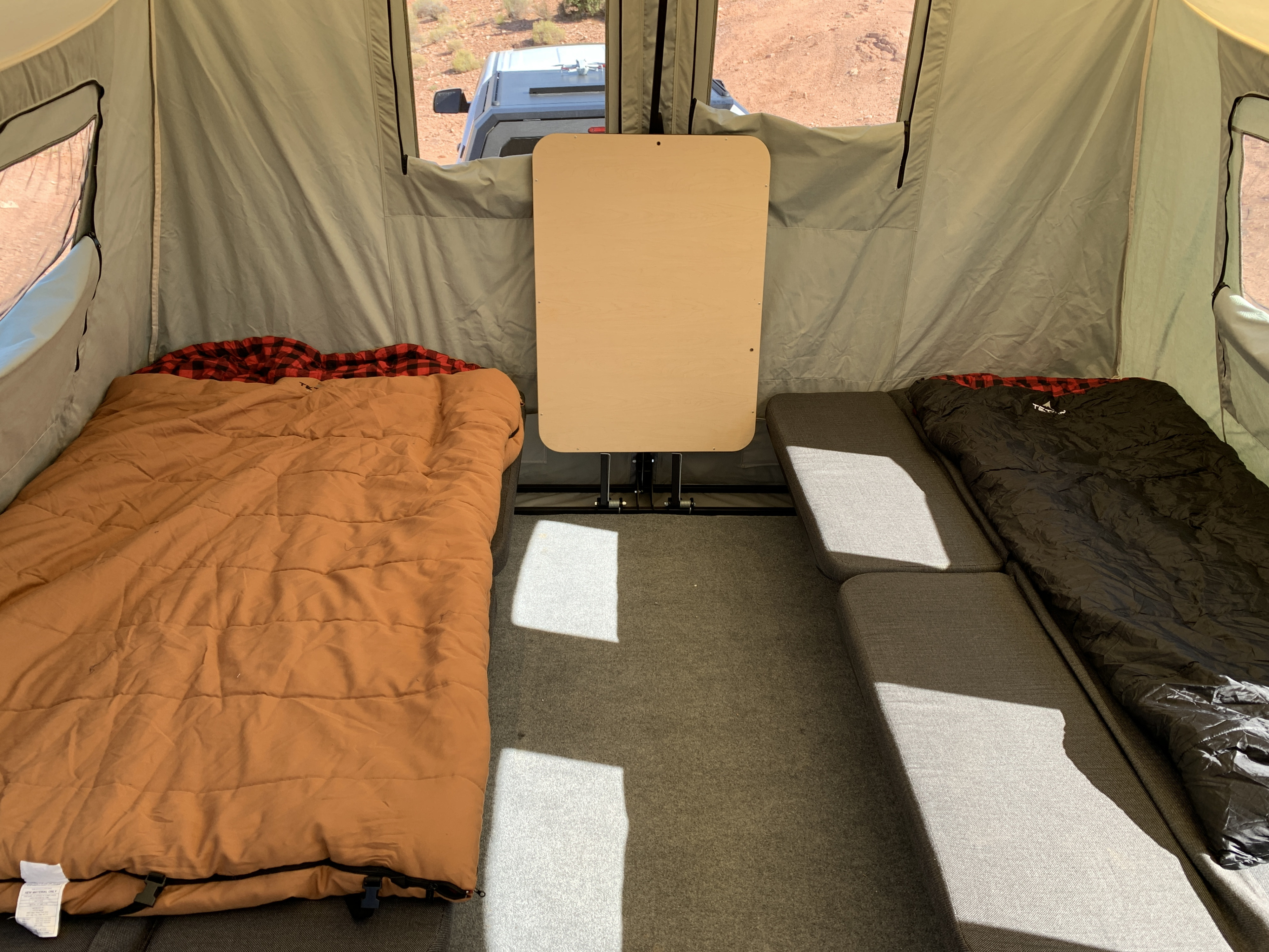 RV rental's spacious interior: two comfortable beds, central table, and scenic desert views for your trip.. Jumping Jack Jumping Jack 6x12 12' Tent Mid Blackout 2022