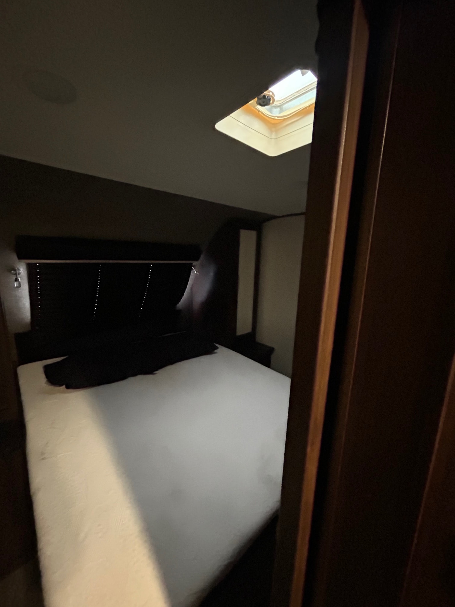 Inside an RV rental: a comfy bedroom with a white mattress, dark bedding, and ceiling skylight.. Jayco White Hawk 2019
