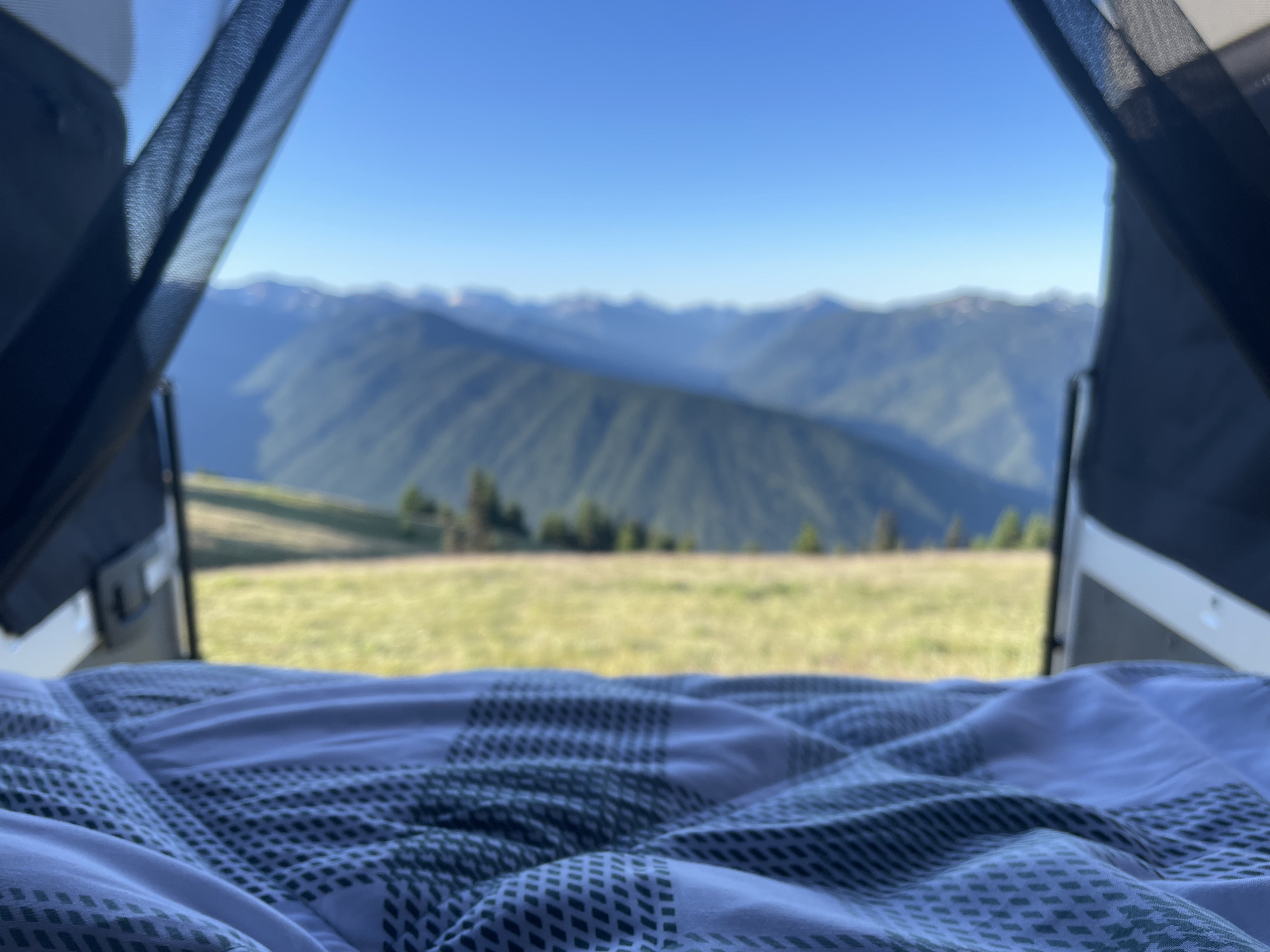 Wake up to epic mountain views from a comfortable RV rental bed! Lush green fields, distant peaks, and a vast blue sky await.. Other Other 2022