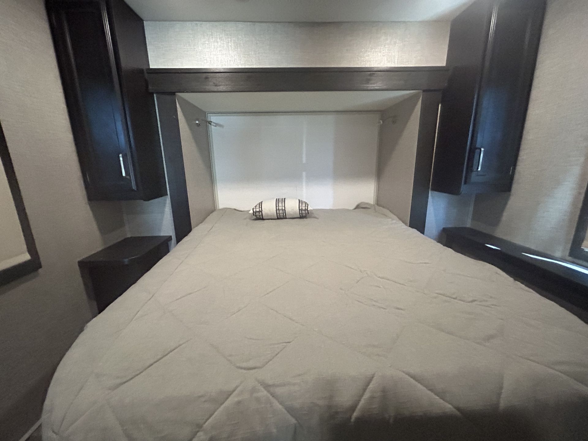 Experience comfort in this RV rental bedroom: bed with light comforter, built-in cabinets & nightstands.. Jayco Greyhawk 2022