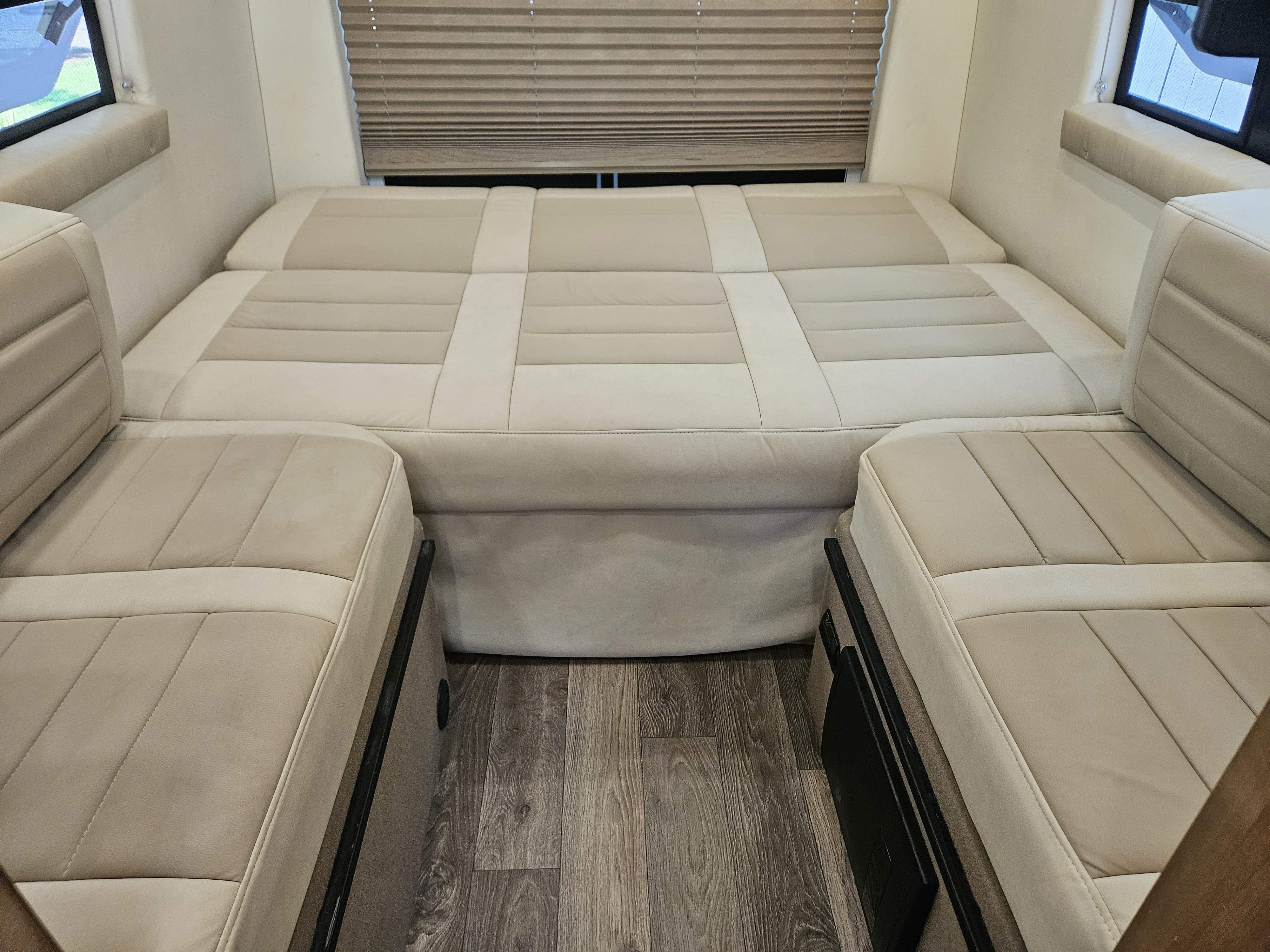 Comfortable RV rental interior featuring a light-colored, upholstered bed/dinette conversion area and wood-look flooring.. Coachman Galleria 24FL 2021